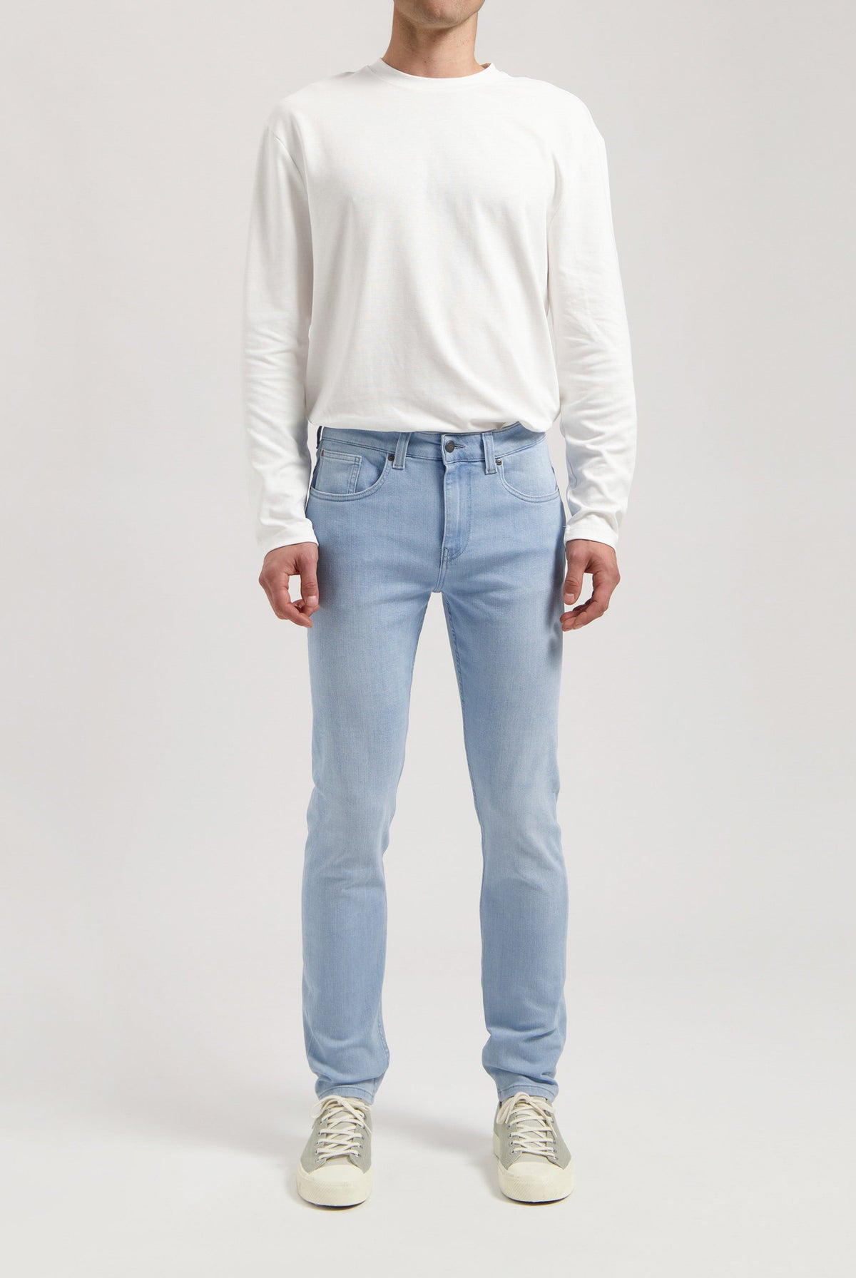 Sustainable MUD Jeans in classic blue denim, paired with a black jacket and white tee, styled for an ethical urban look.