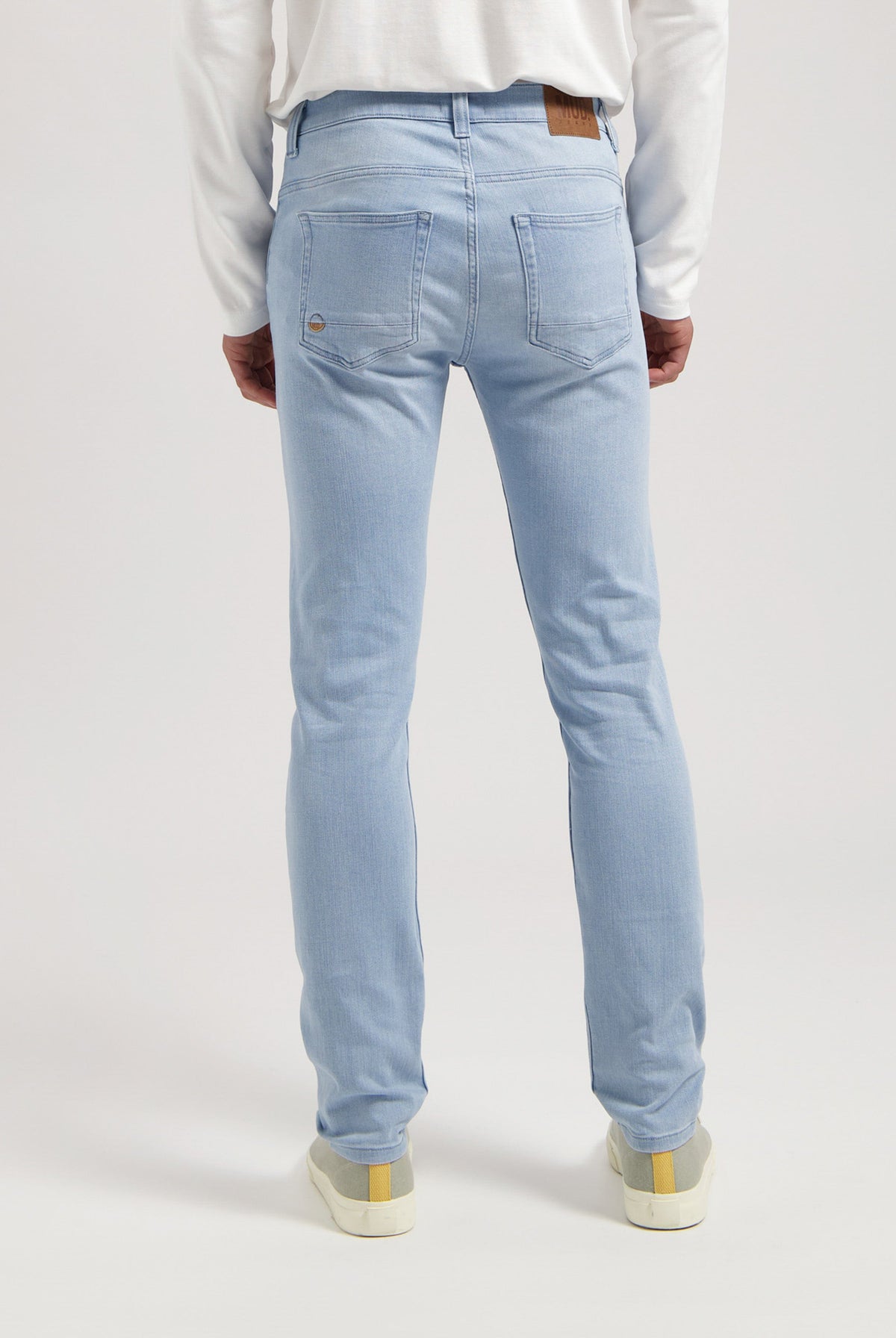 Sustainable MUD Jeans made from organic cotton, in a dark blue wash, paired with a classic gray sweater for an ethical style.