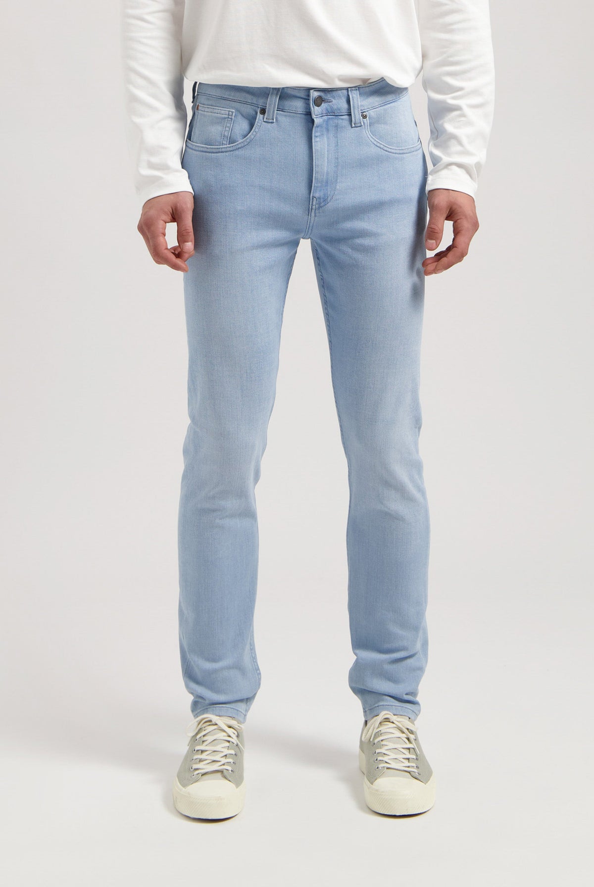 Sustainable MUD Jeans in dark denim, featuring a classic straight fit, paired with a light gray sweater and black boots.