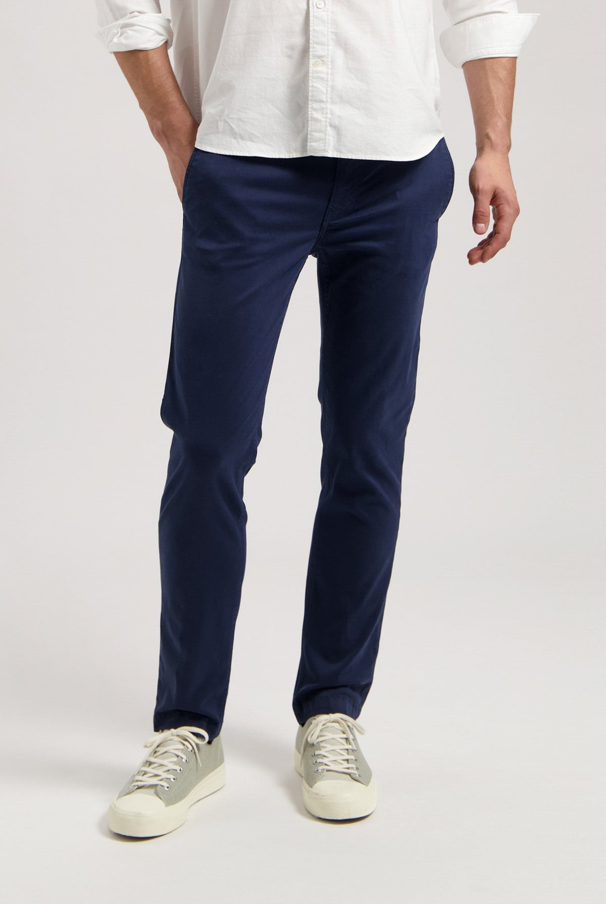 Sustainable MUD Jeans in dark gray denim, crafted ethically, paired with black sneakers and a black T-shirt.