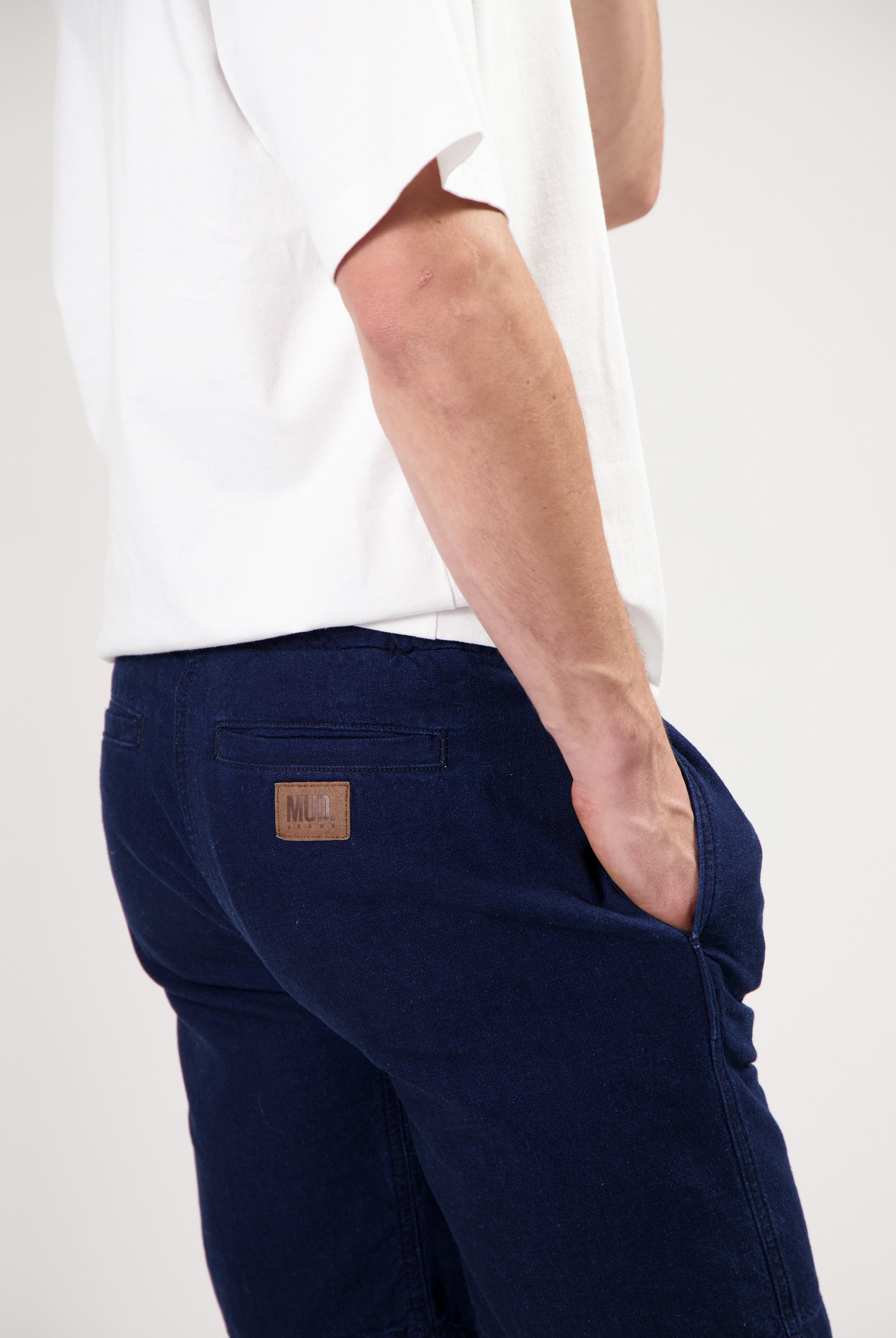 Sustainable MUD Jeans in dark blue denim, made from ethical materials, modeled with a plain white tee and white sneakers.