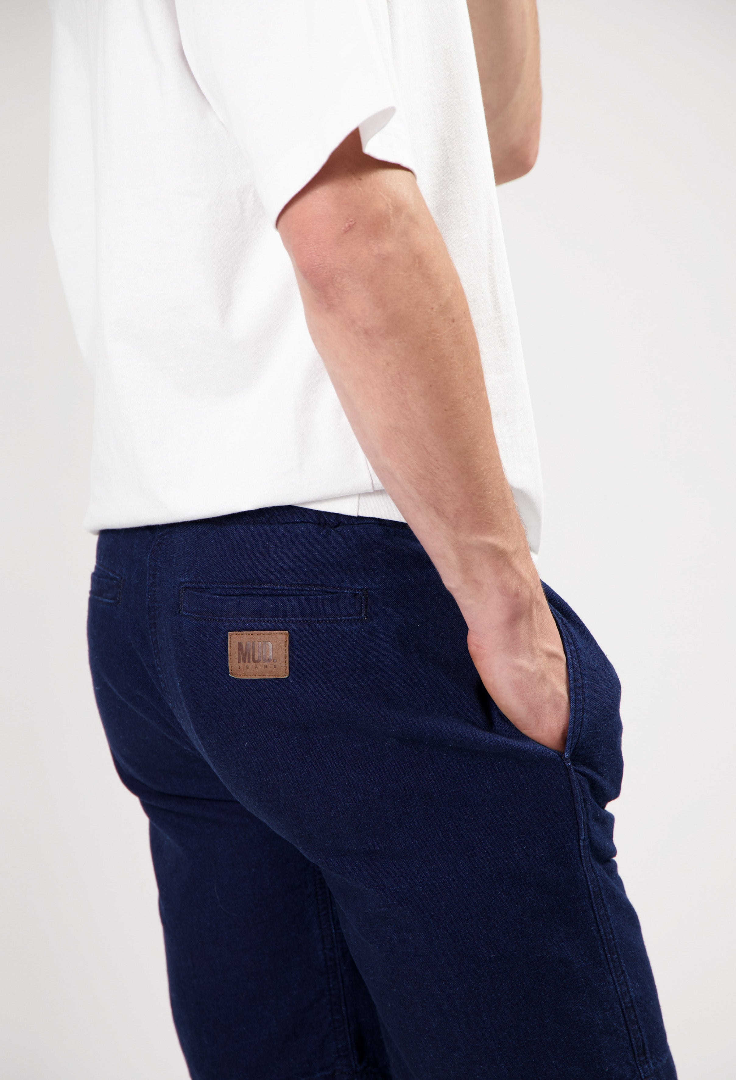 Sustainable MUD Jeans in dark blue denim, made from ethical materials, modeled with a plain white tee and white sneakers.