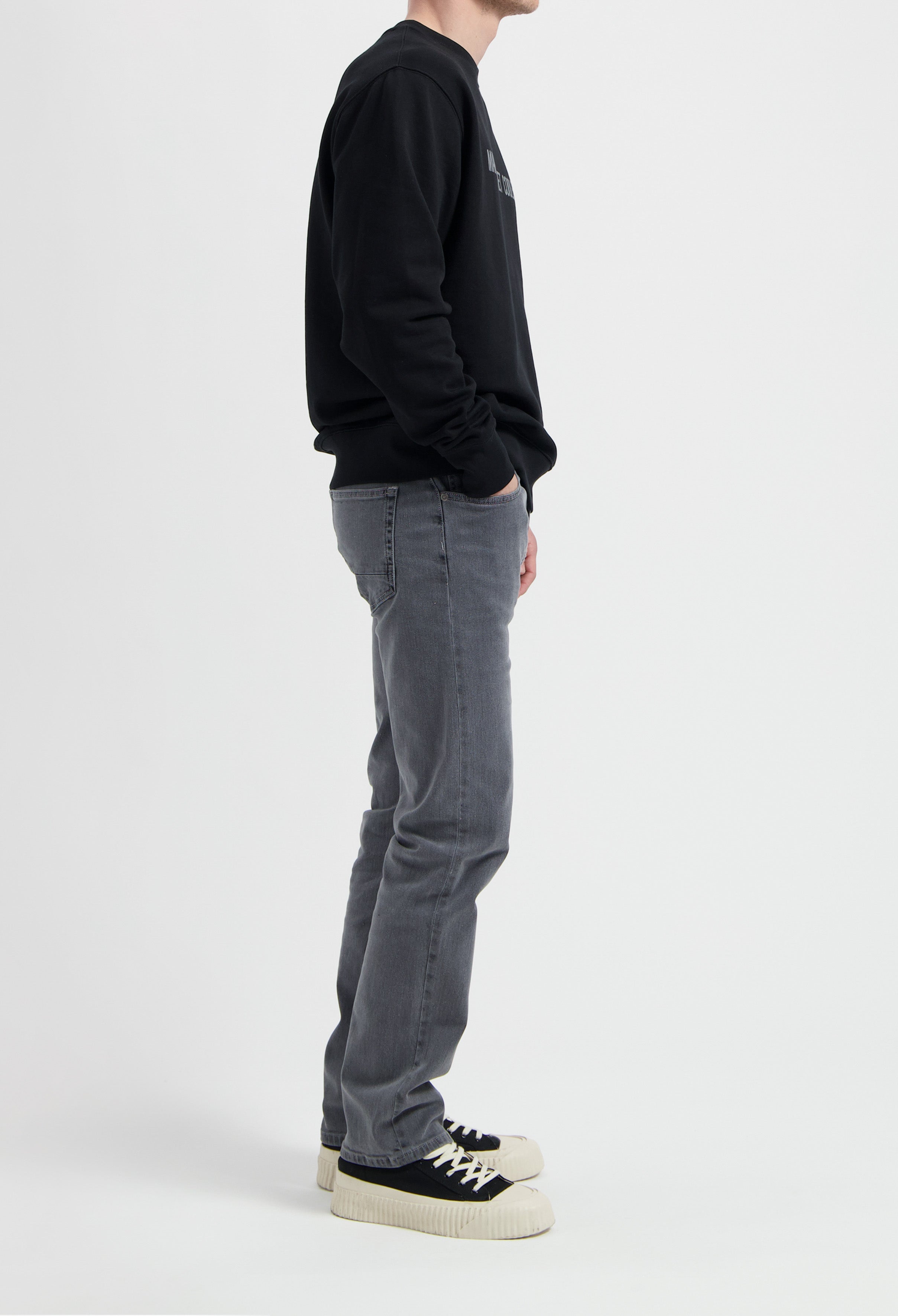 Sustainable MUD Jeans in light blue denim, crafted ethically from organic cotton, shown paired with white sneakers.