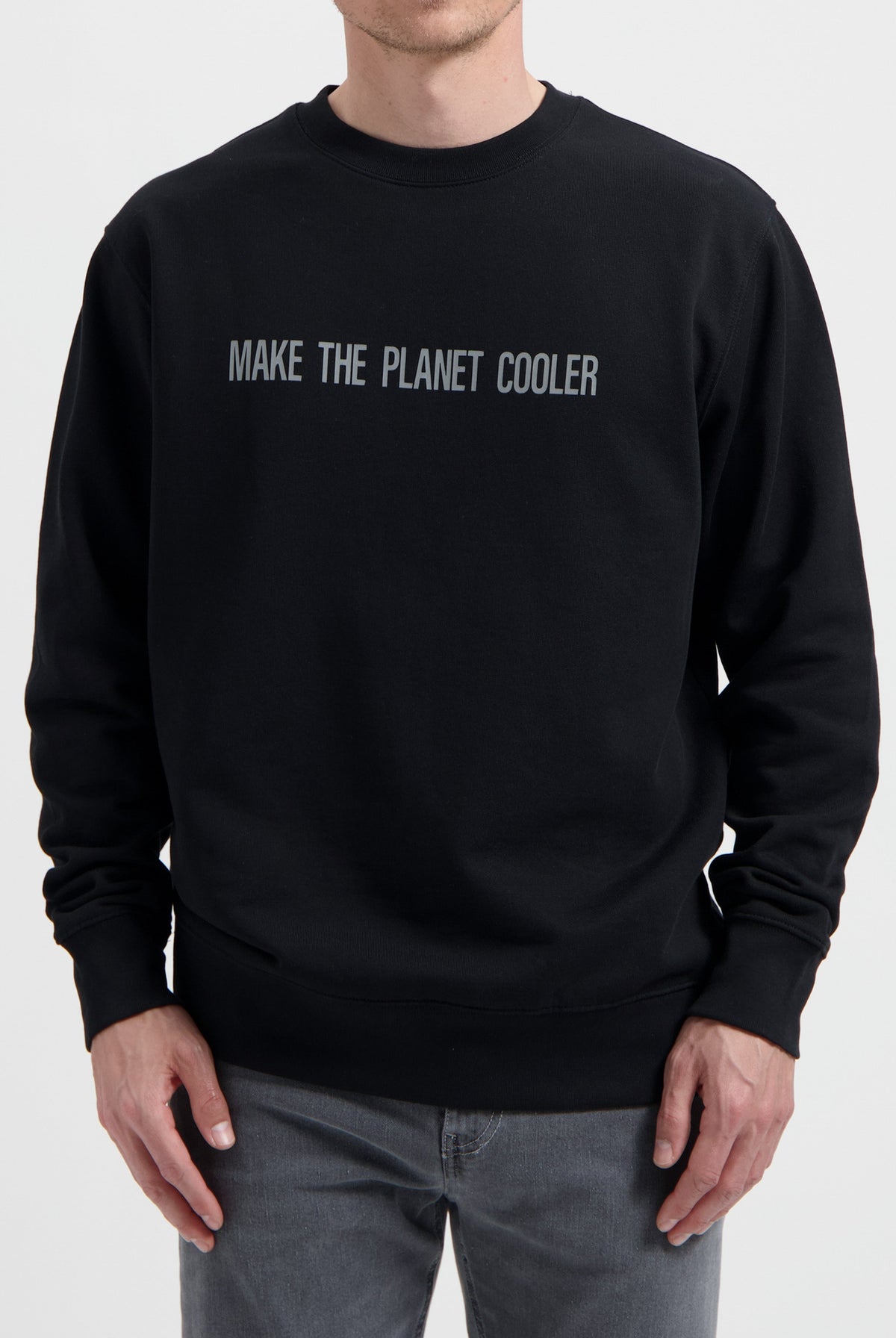 Sustainable MUD Jeans black sweater with "Make the Planet Cooler" slogan, paired with gray denim, ethical fashion choice.