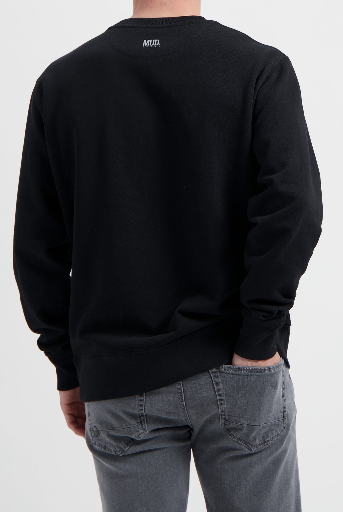 Sustainable MUD Jeans in gray worn with a black ethical sweatshirt, showcasing eco-friendly fashion choices.