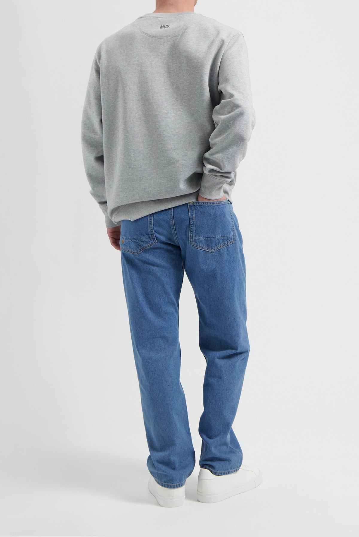 Sustainable MUD Jeans in blue denim, eco-friendly design, paired with a gray sweatshirt, showcasing ethical fashion.