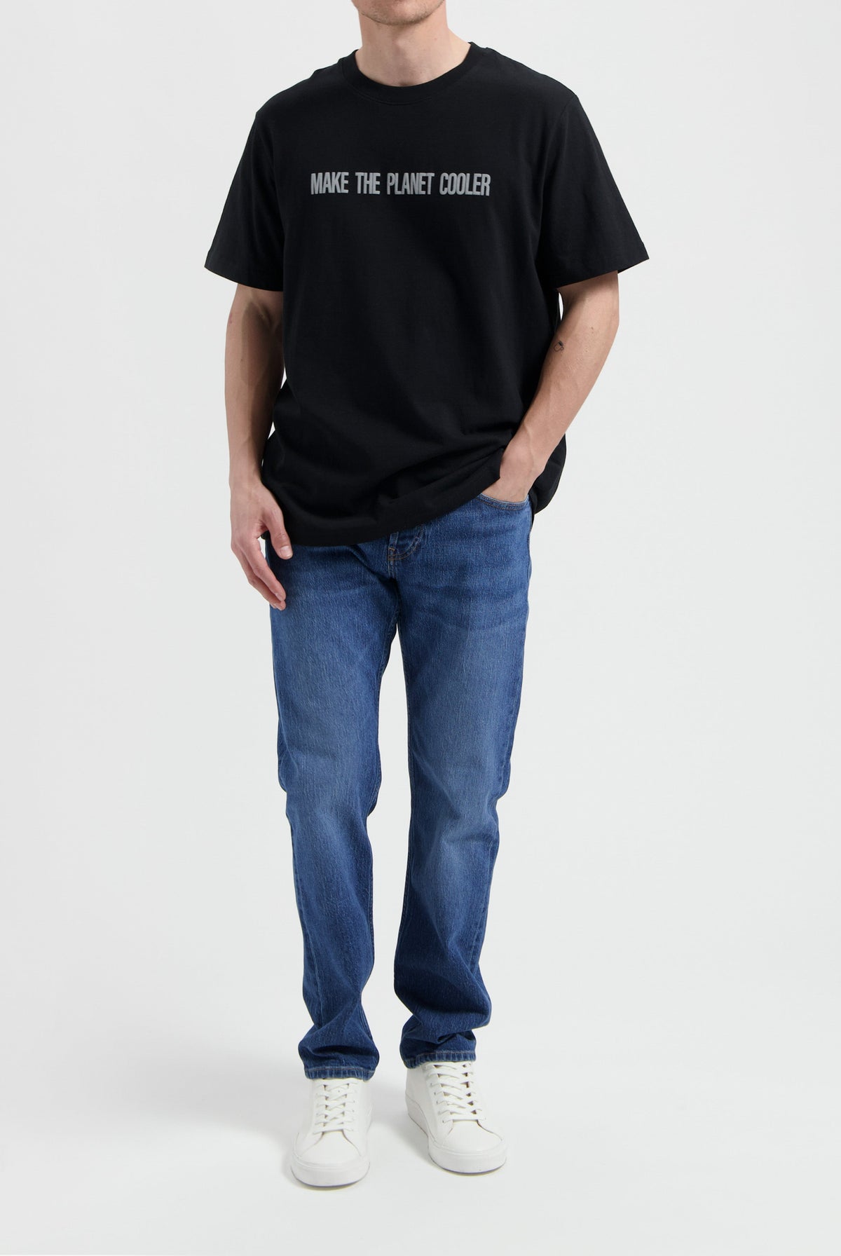 Sustainable MUD Jeans in dark brown, crafted from organic cotton, paired with a white shirt and casual sneakers.