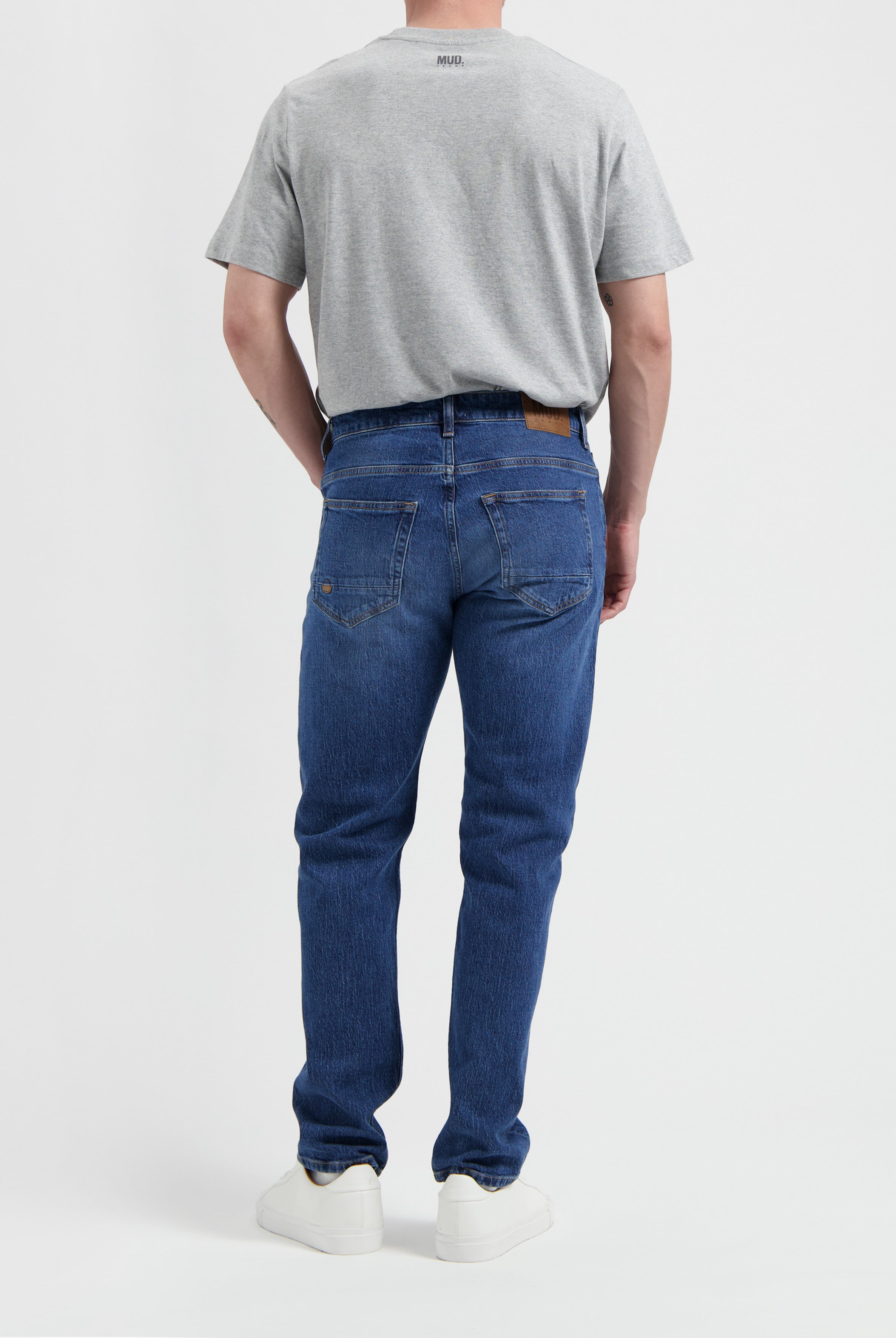 Sustainable MUD Jeans in beige, crafted from organic cotton, offering a slim fit, paired with a casual gray t-shirt.