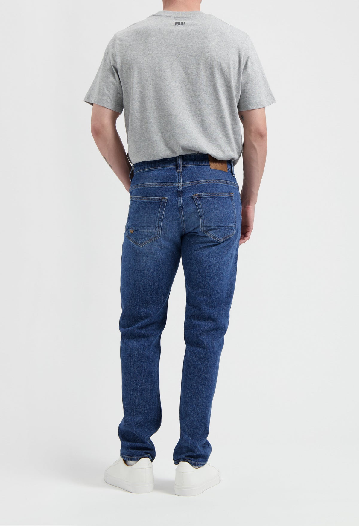 Sustainable MUD Jeans in beige, crafted from organic cotton, offering a slim fit, paired with a casual gray t-shirt.