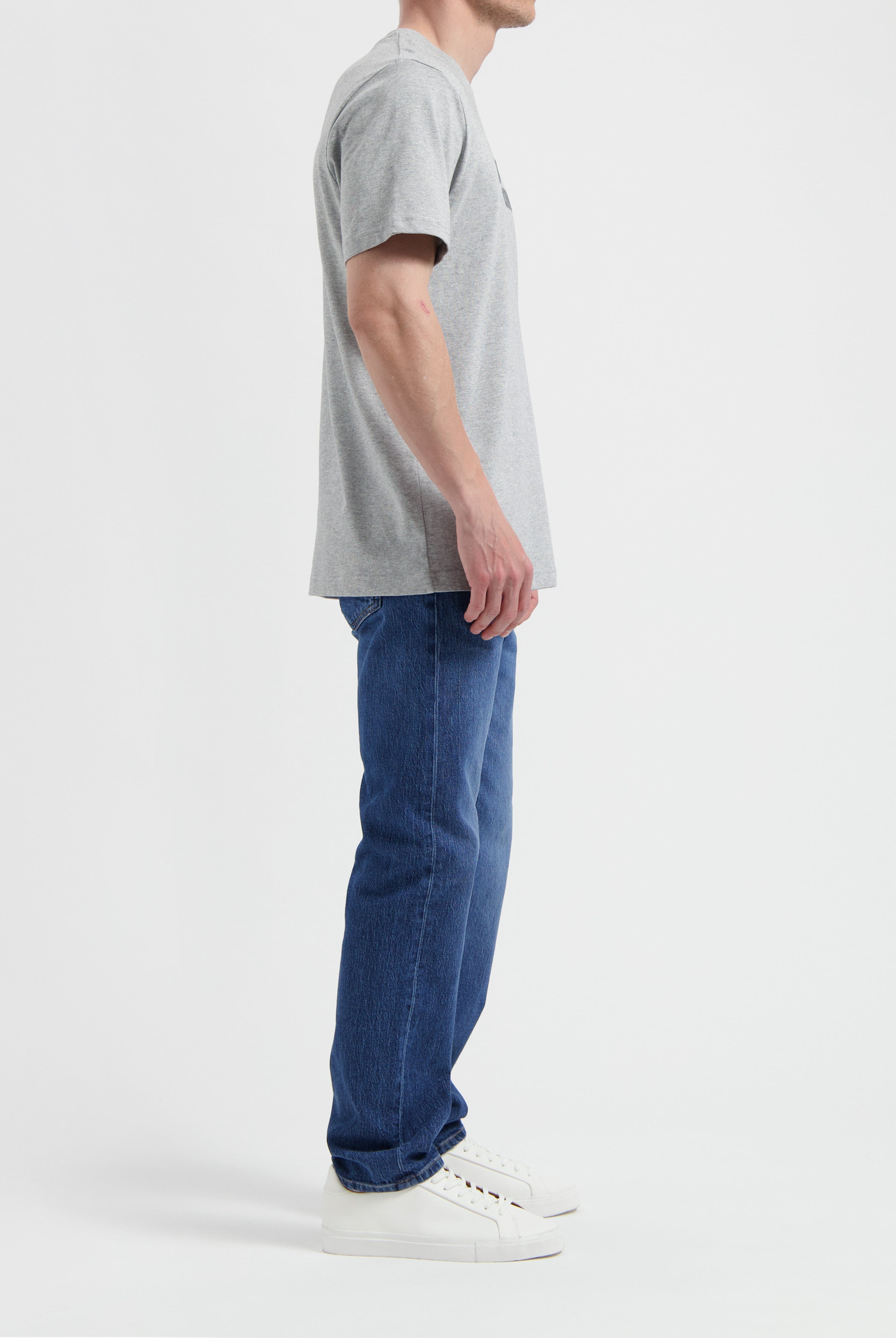Sustainable MUD Jeans featuring beige denim, crafted ethically, paired with a casual gray t-shirt and sneakers.