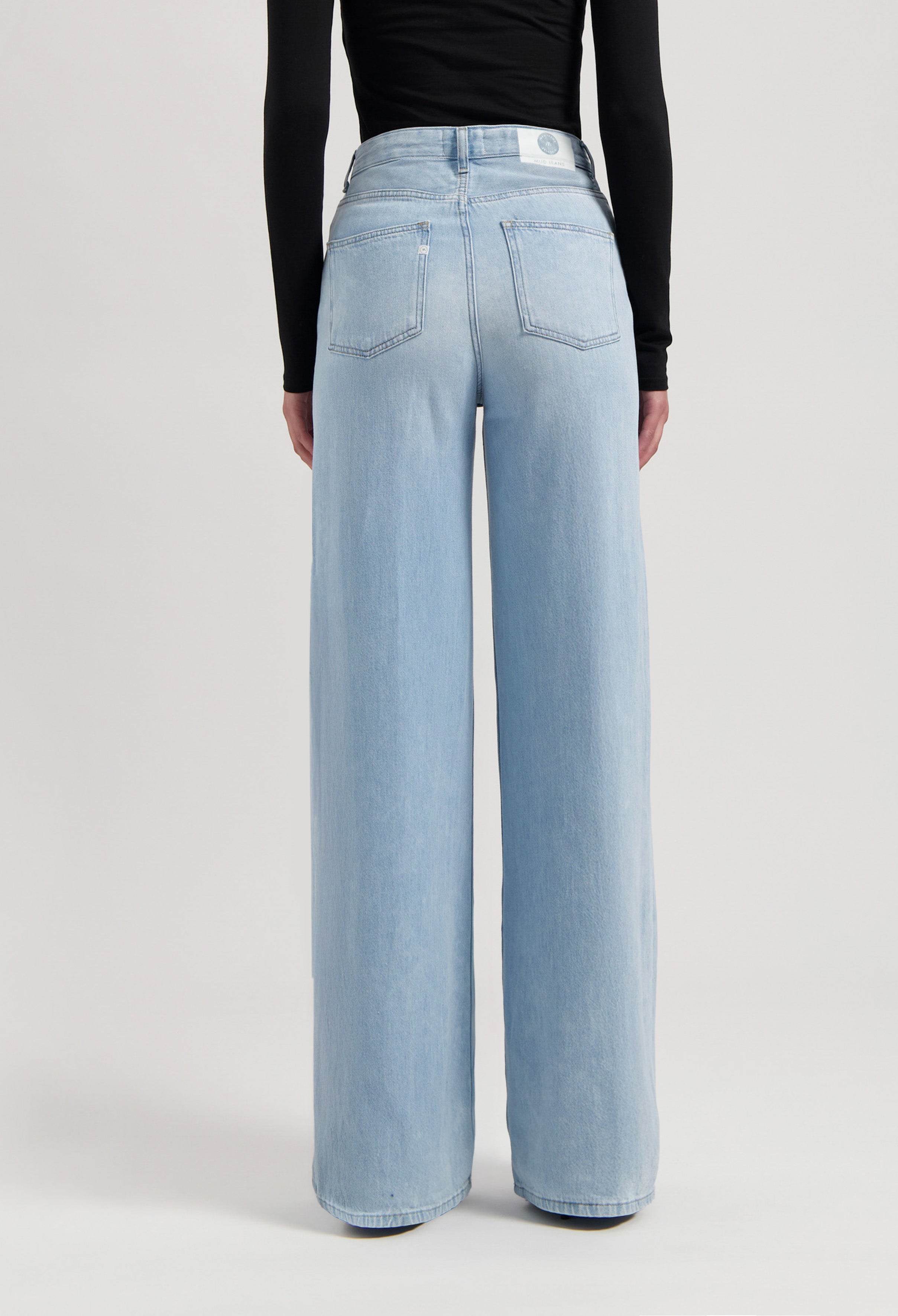 Light blue, wide-leg denim jeans made from organic cotton, shown worn with a black, long-sleeve top.