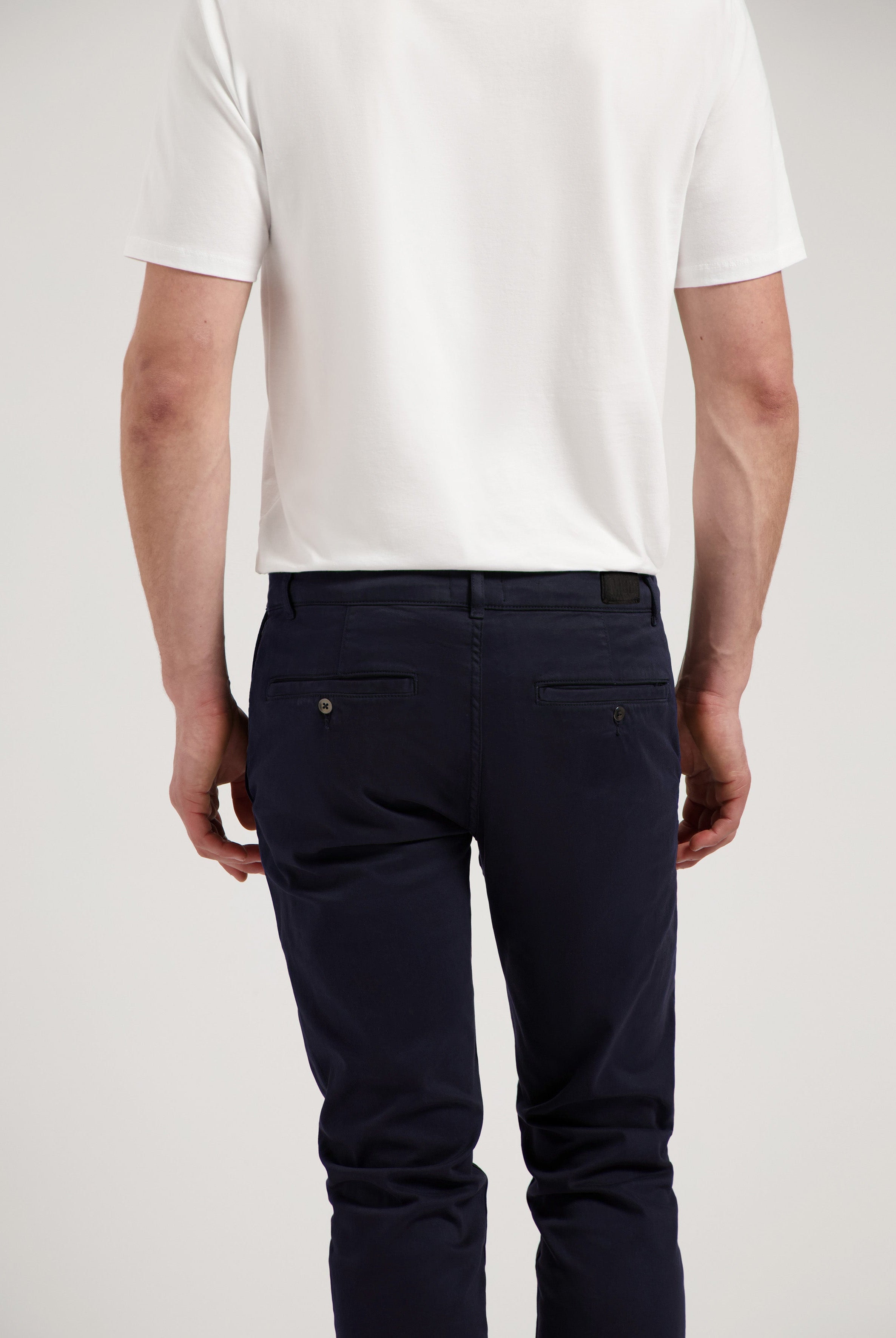 Sustainable MUD Jeans in white denim, crafted ethically from organic cotton, paired with a navy blue shirt.