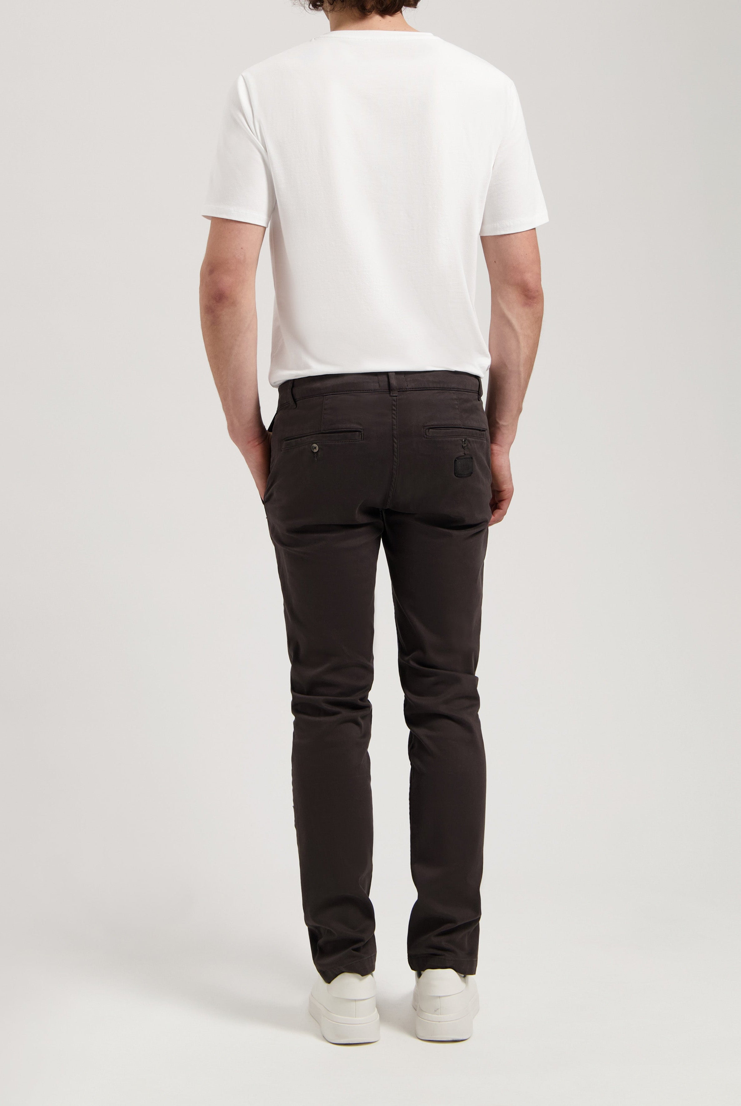Sustainable MUD Jeans in dark gray denim, made from organic cotton, showcasing classic straight fit, worn with white top.