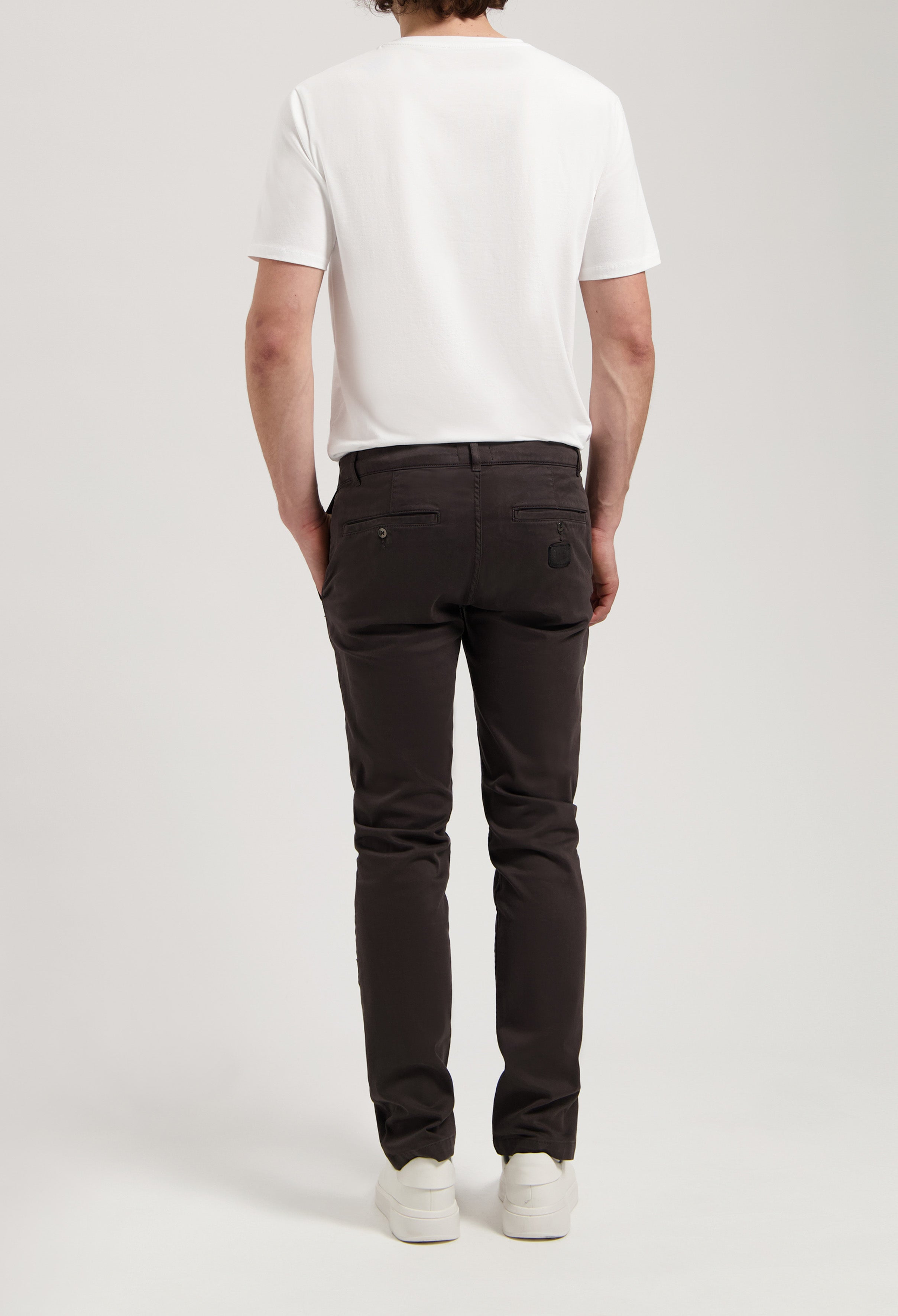 Sustainable MUD Jeans in dark gray denim, made from organic cotton, showcasing classic straight fit, worn with white top.