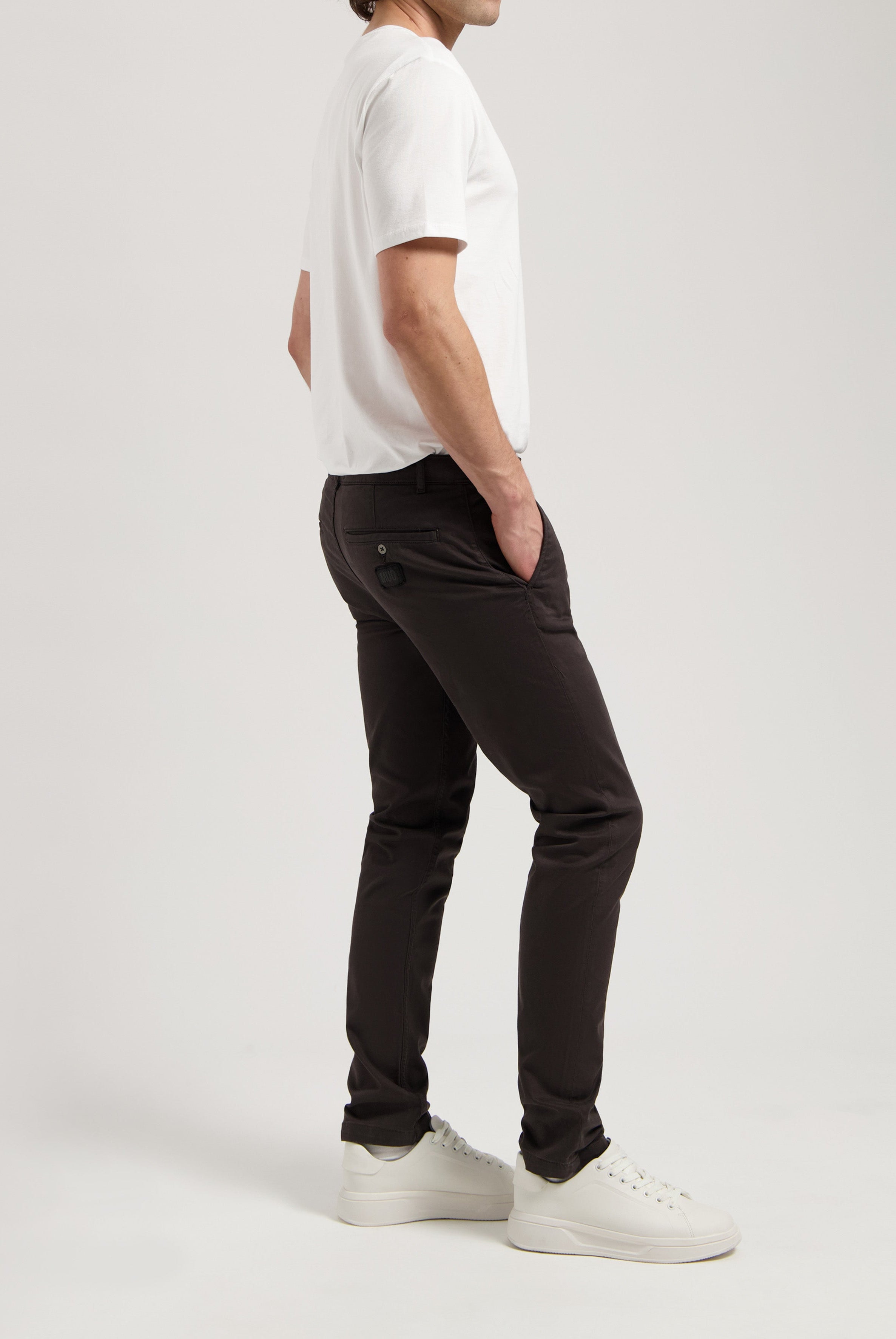 Sustainable MUD Jeans in dark gray denim, featuring an ethical fit, paired with a white long-sleeve shirt.
