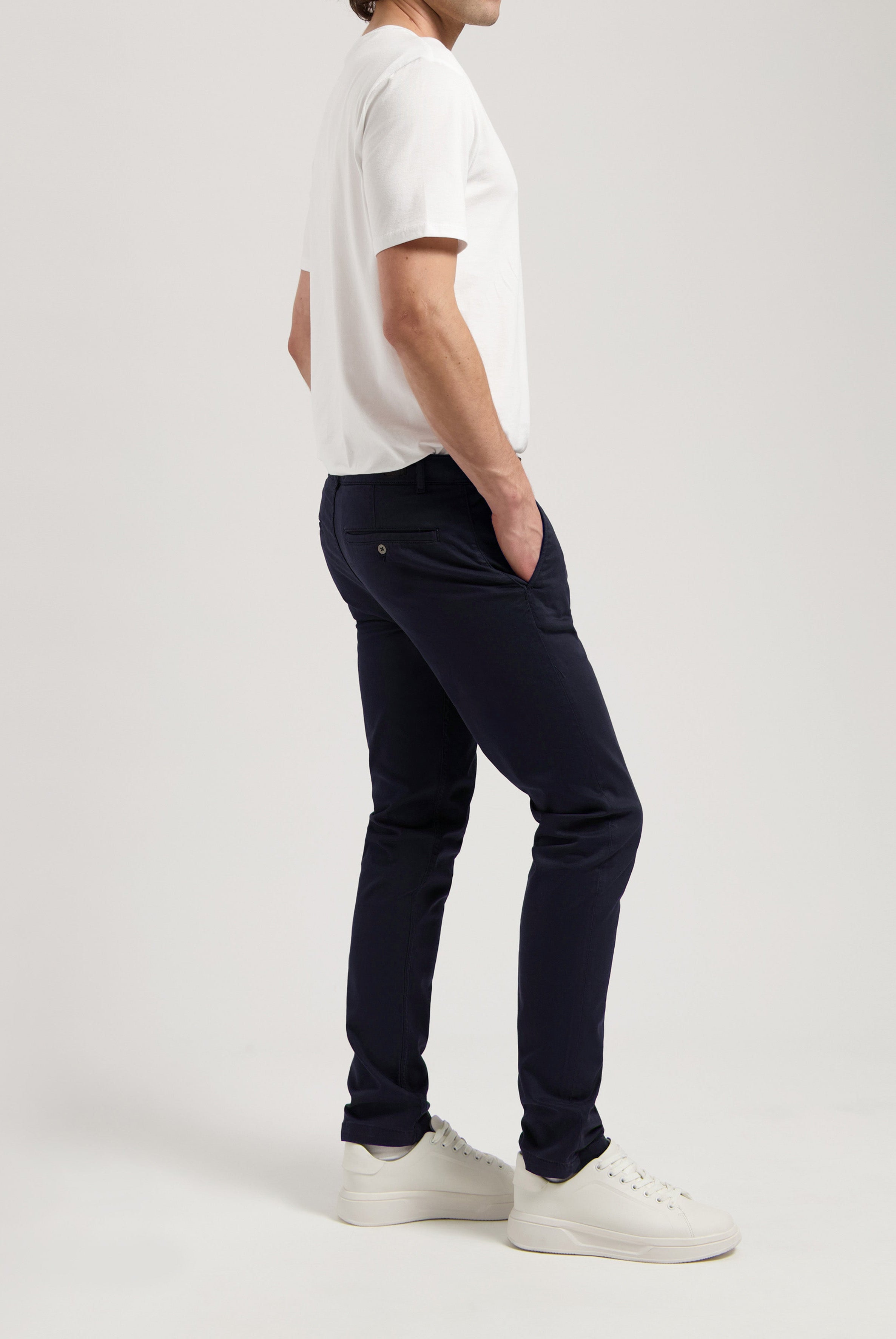 Sustainable MUD Jeans in white denim, crafted ethically, paired with a navy t-shirt and black loafers.