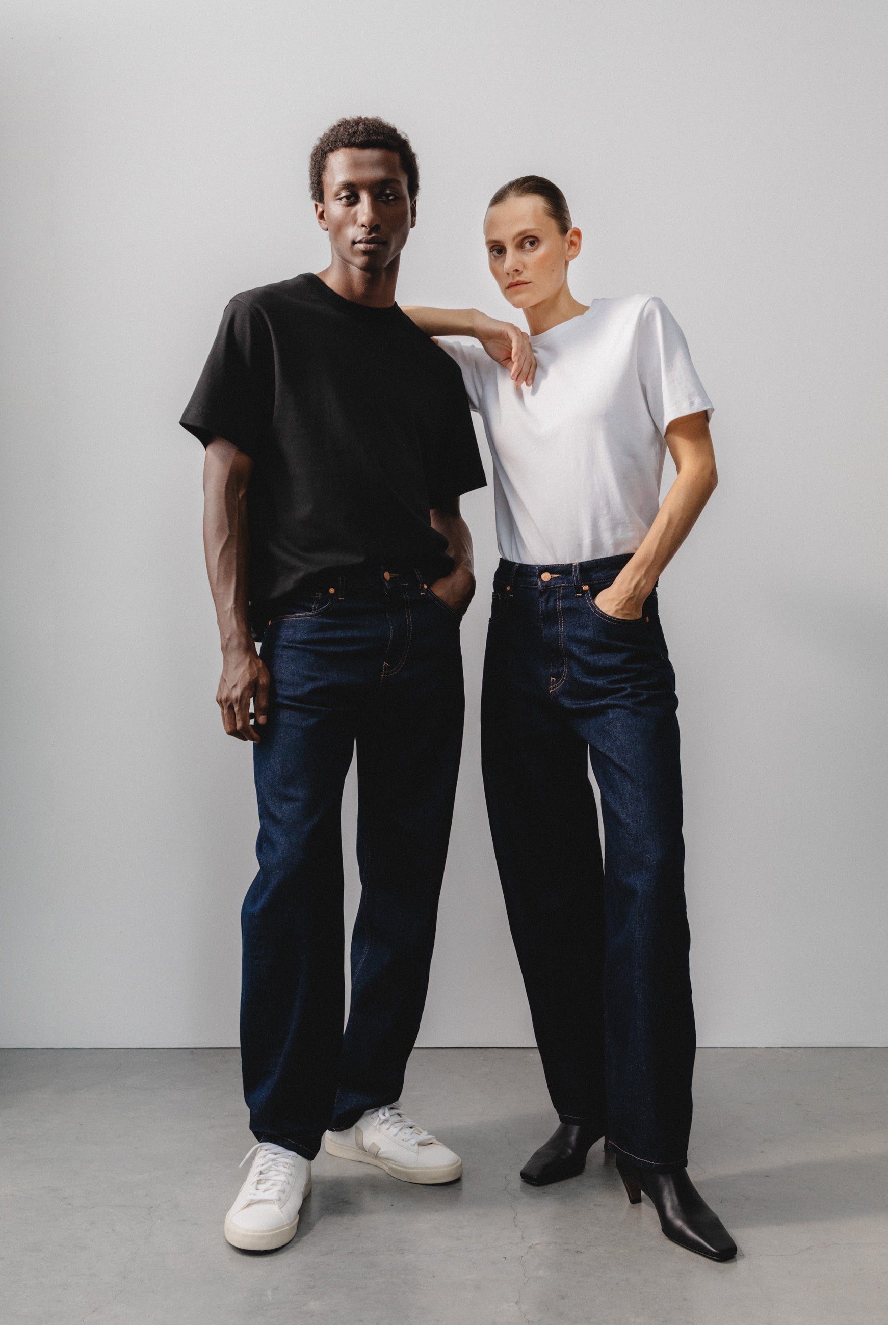 Sustainable MUD Jeans in dark wash denim, crafted ethically, paired with a cozy gray sweater, viewed from the back.