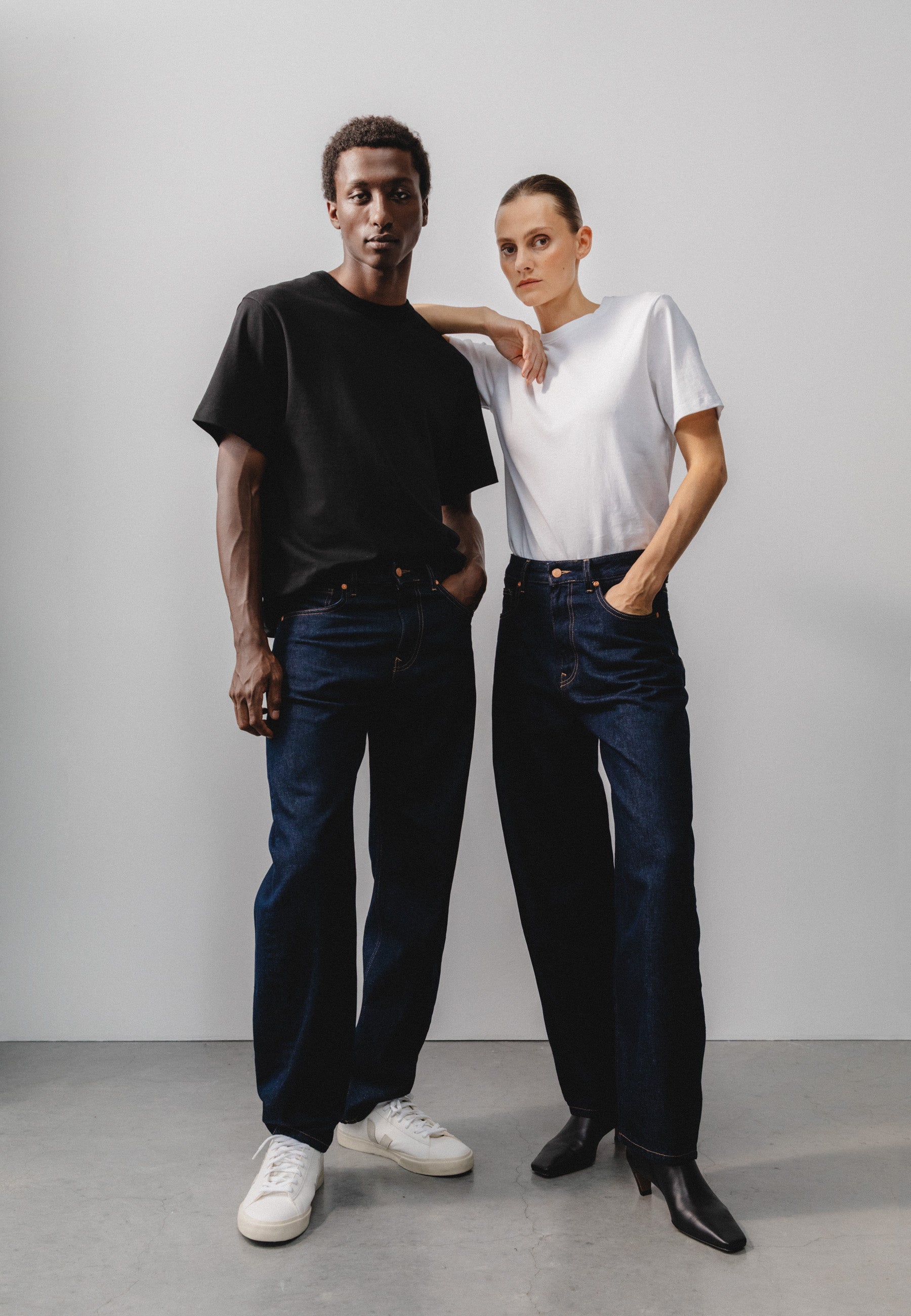 Sustainable MUD Jeans in dark wash denim, crafted ethically, paired with a cozy gray sweater, viewed from the back.