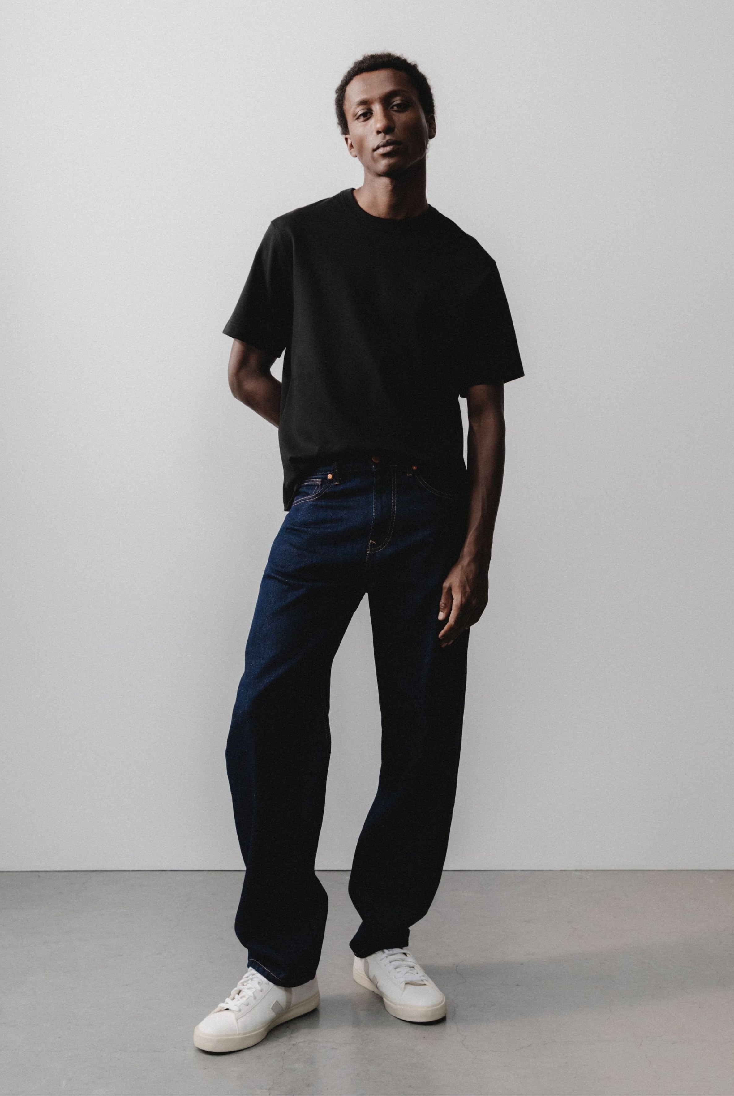 Sustainable MUD Jeans made of organic cotton in sleek black denim, paired with a gray sweater for an ethical style.