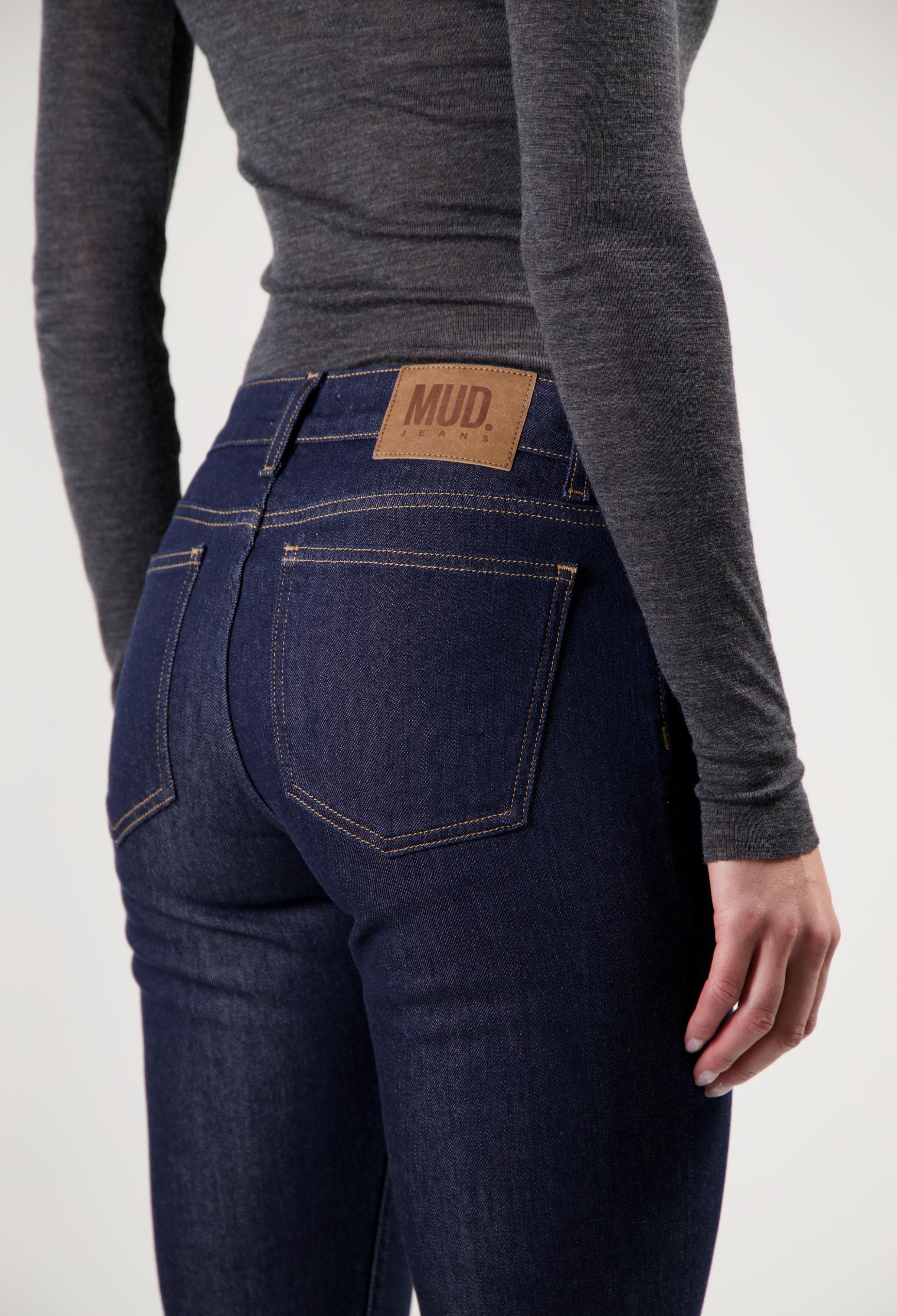Dark blue MUD Jeans made from organic cotton, showing the back view worn with a fitted long-sleeve gray top.