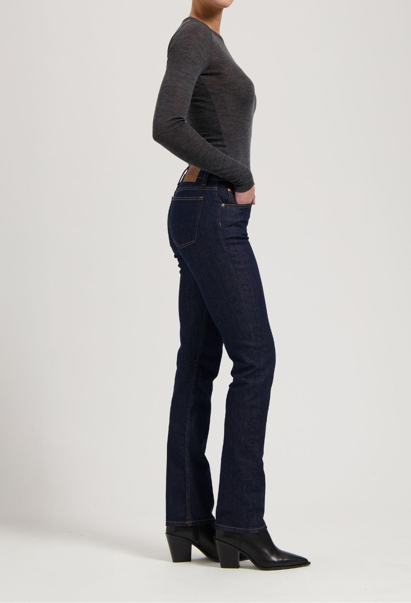 Dark blue slim-fit jeans and black boots paired with a dark gray, long-sleeve top, showcasing casual modern fashion.