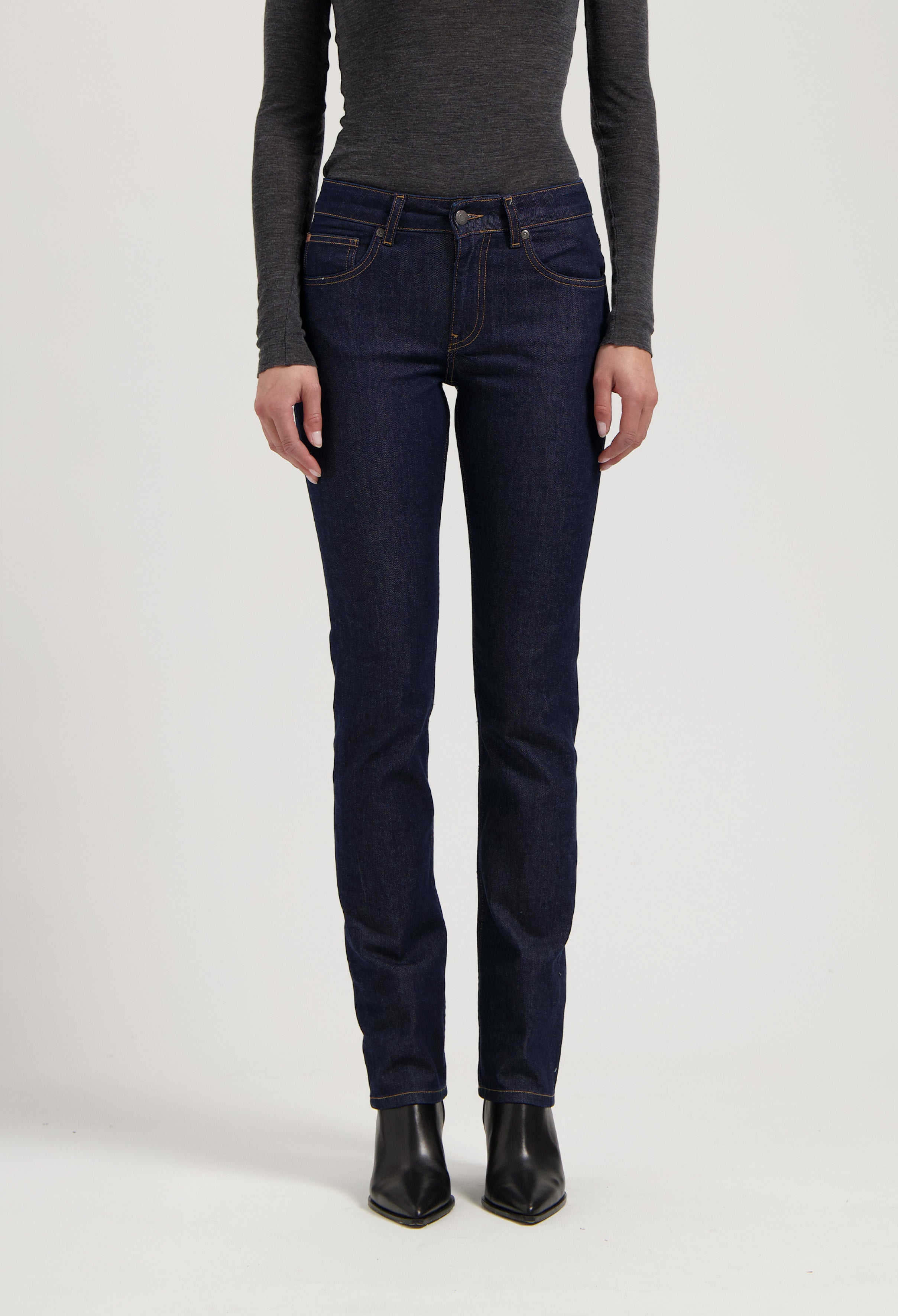 Dark blue, slim-fit denim jeans paired with a charcoal gray long-sleeve top, styled with black ankle boots.