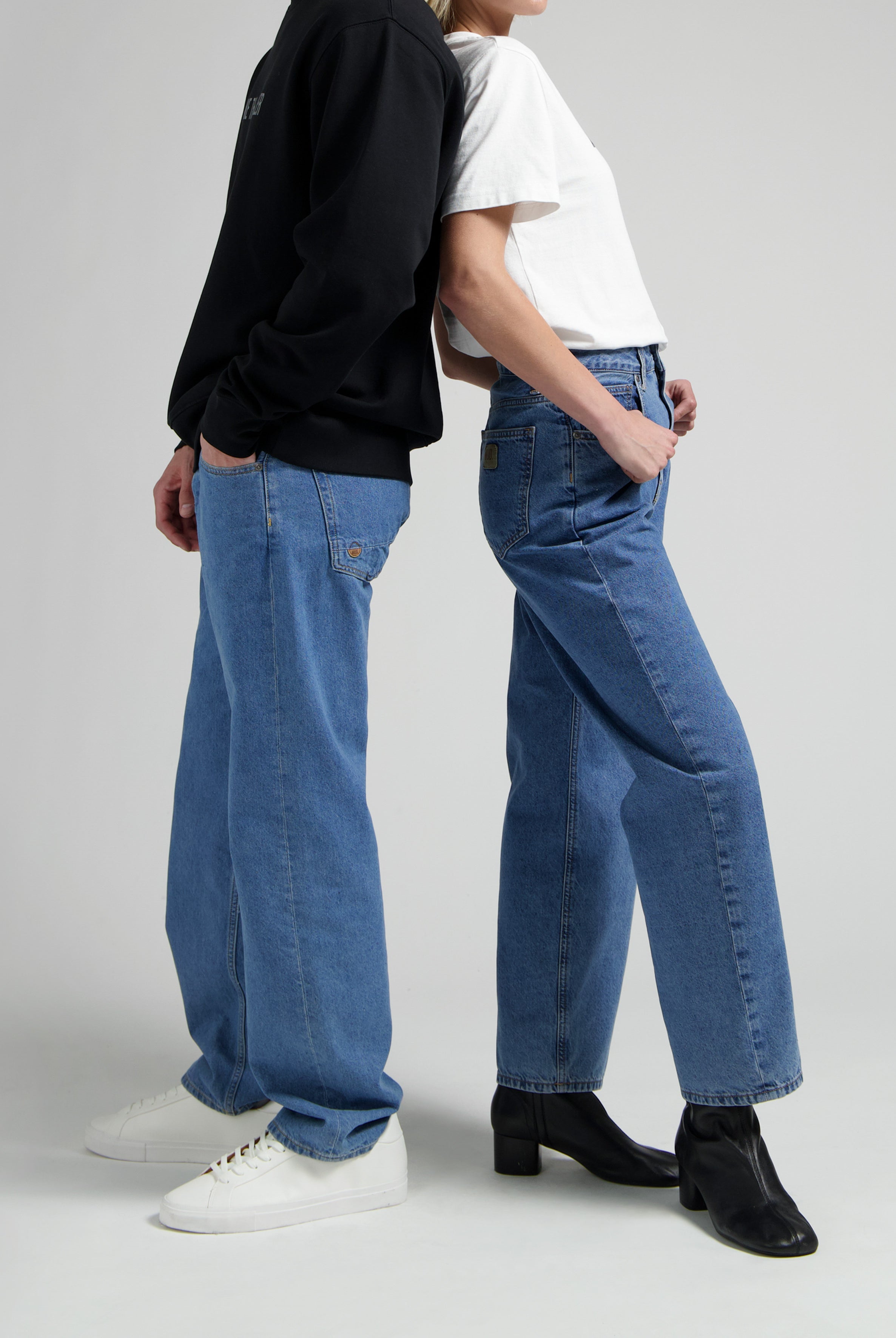 Casual blue jeans outfit with white tee and black sweatshirt, styled with white sneakers and black heeled boots.