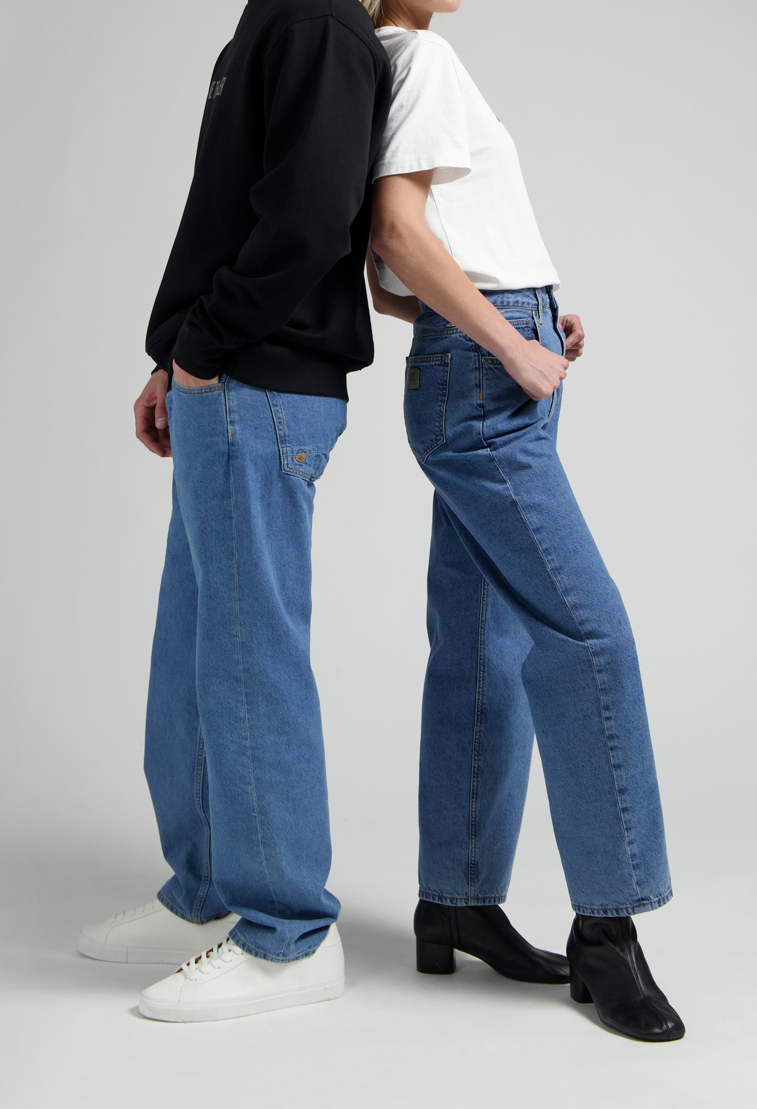 Casual blue jeans outfit with white tee and black sweatshirt, styled with white sneakers and black heeled boots.