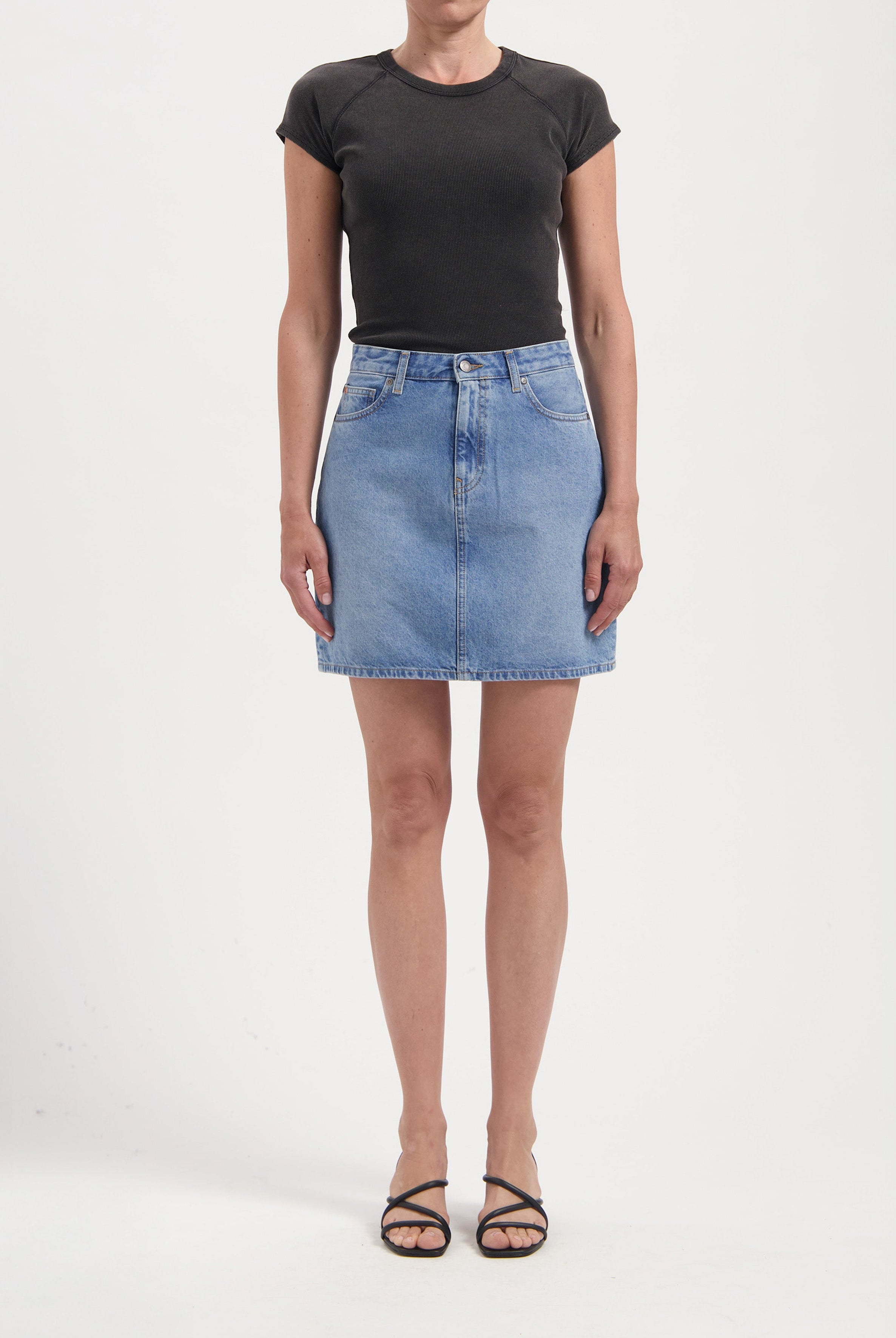 Woman wearing a light blue denim skirt paired with a fitted black short-sleeve top, showcasing casual chic style.