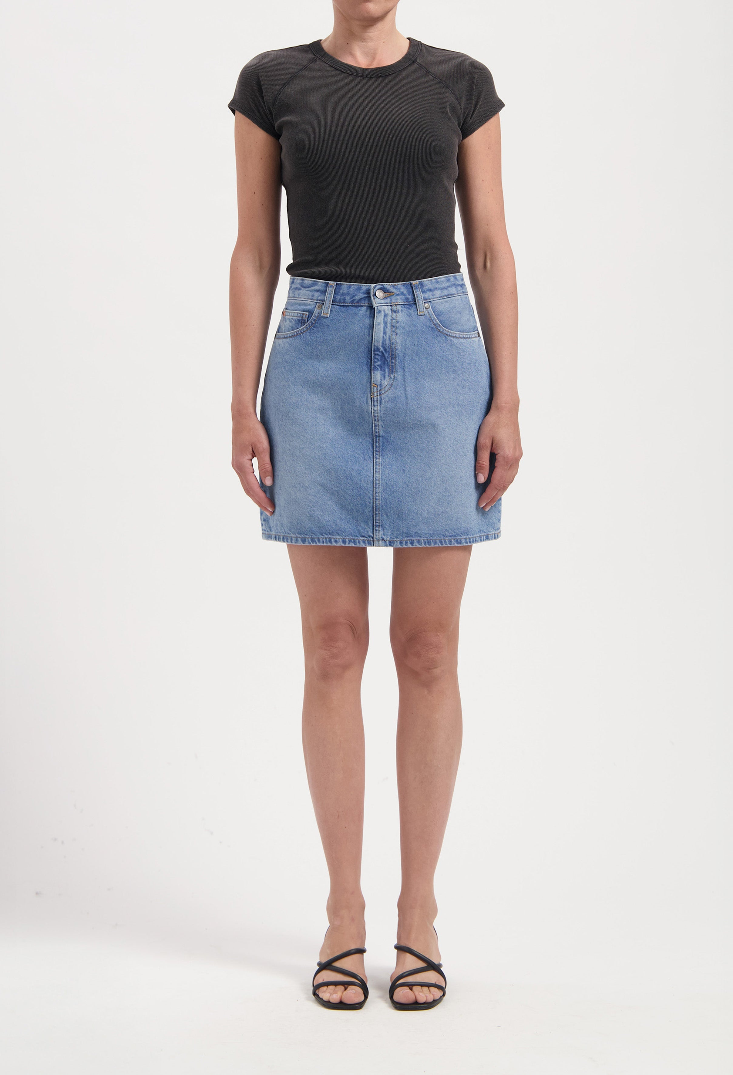 Woman wearing a light blue denim skirt paired with a fitted black short-sleeve top, showcasing casual chic style.