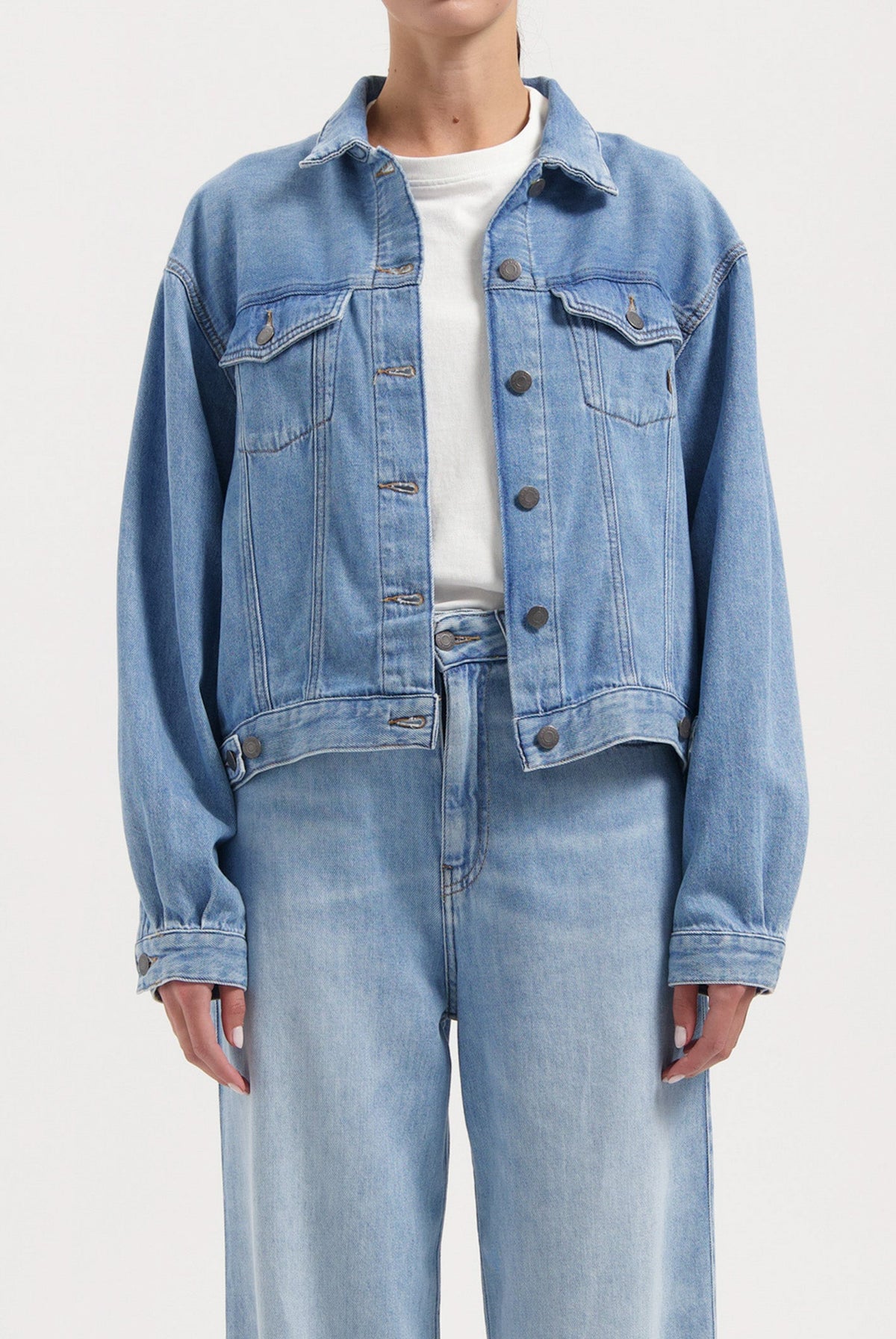 Light blue denim jacket and jeans set, featuring classic button-down design and relaxed fit, worn with a basic white top.