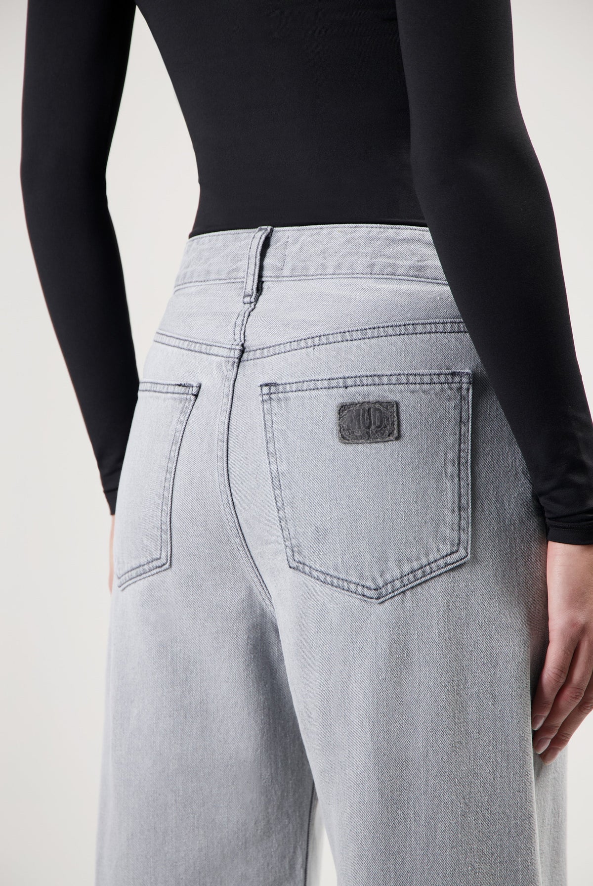 Light gray high-waisted denim jeans with wide-cut legs, paired with a fitted black long-sleeve top.
