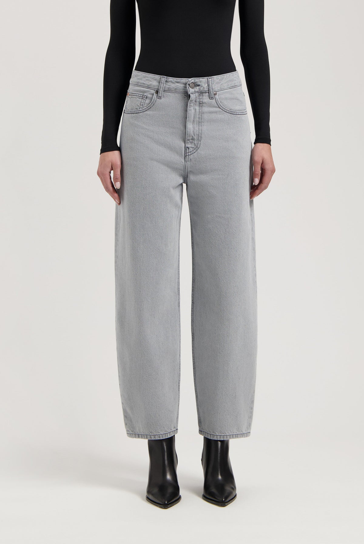 Wide-leg light gray jeans paired with a sleek black long-sleeve top and pointy black leather ankle boots.