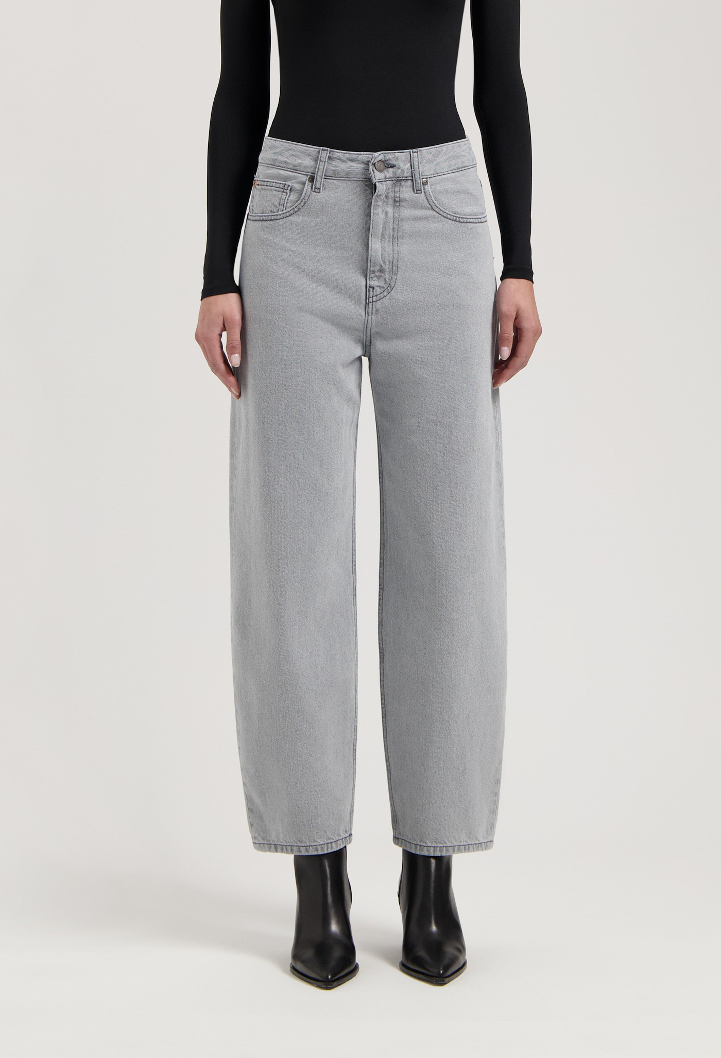 Wide-leg light gray jeans paired with a sleek black long-sleeve top and pointy black leather ankle boots.