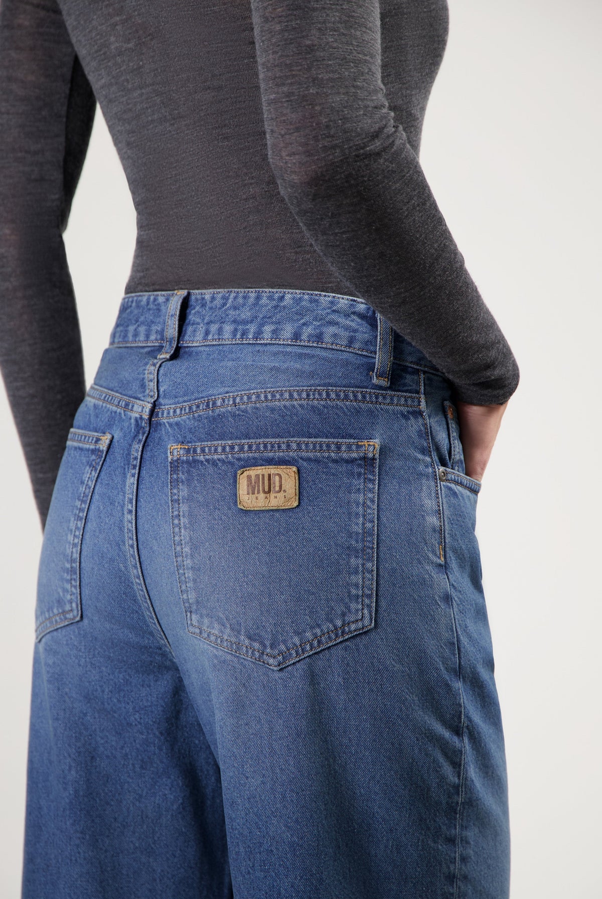 Dark blue, wide-leg MUD Jeans crafted from organic cotton, shown with a fitted charcoal gray long-sleeve top.