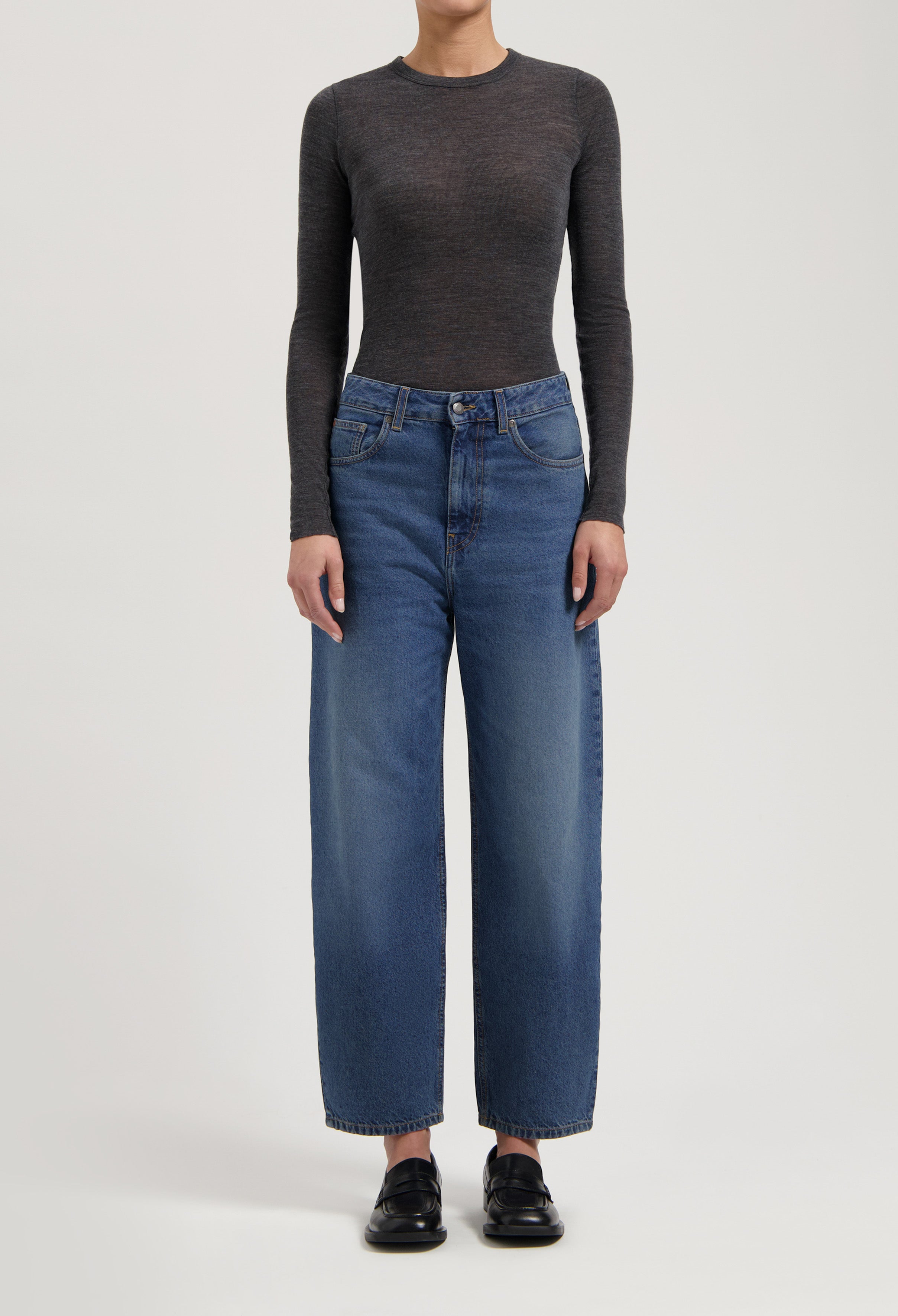 Dark gray long-sleeve top paired with high-waisted wide-leg blue jeans and black loafers, showcasing casual style.