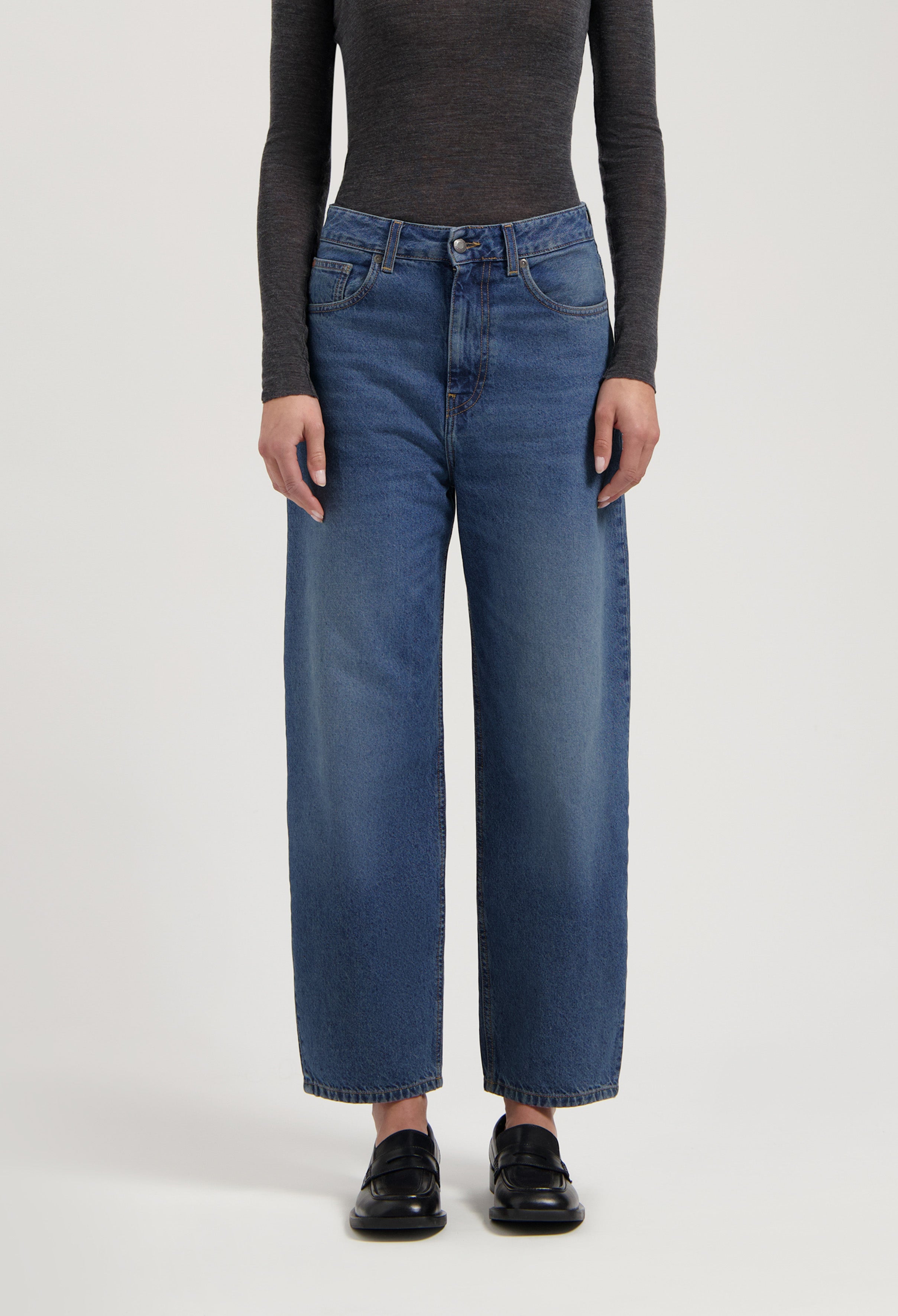 Casual high-waisted wide-leg jeans in classic blue denim paired with a fitted long-sleeve charcoal gray top and black loafers.