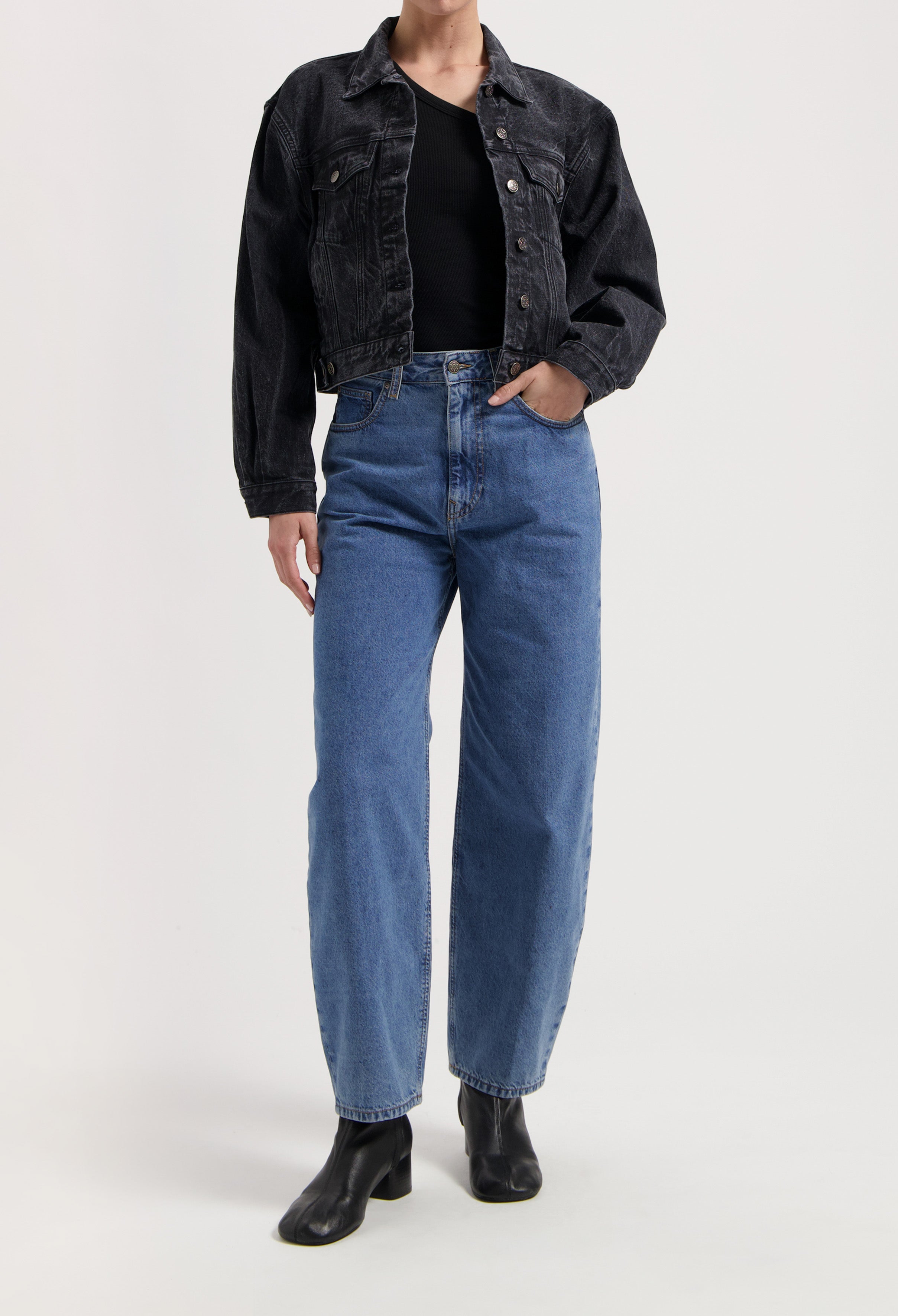 Casual outfit featuring high-waisted blue jeans, black top, and dark denim jacket paired with black ankle boots.