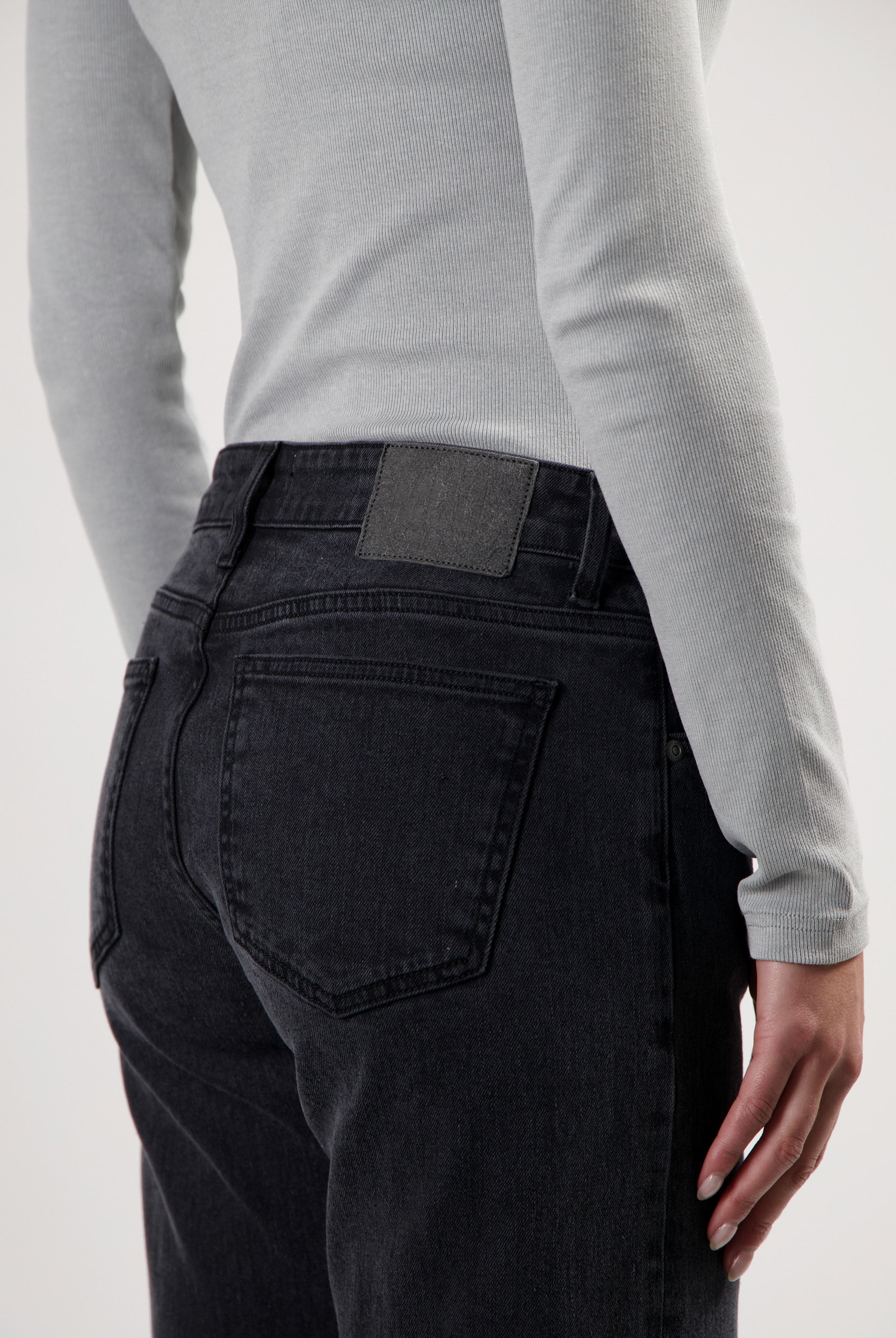 Dark blue jeans with a high-waisted fit, worn with a light gray ribbed long-sleeve top.
