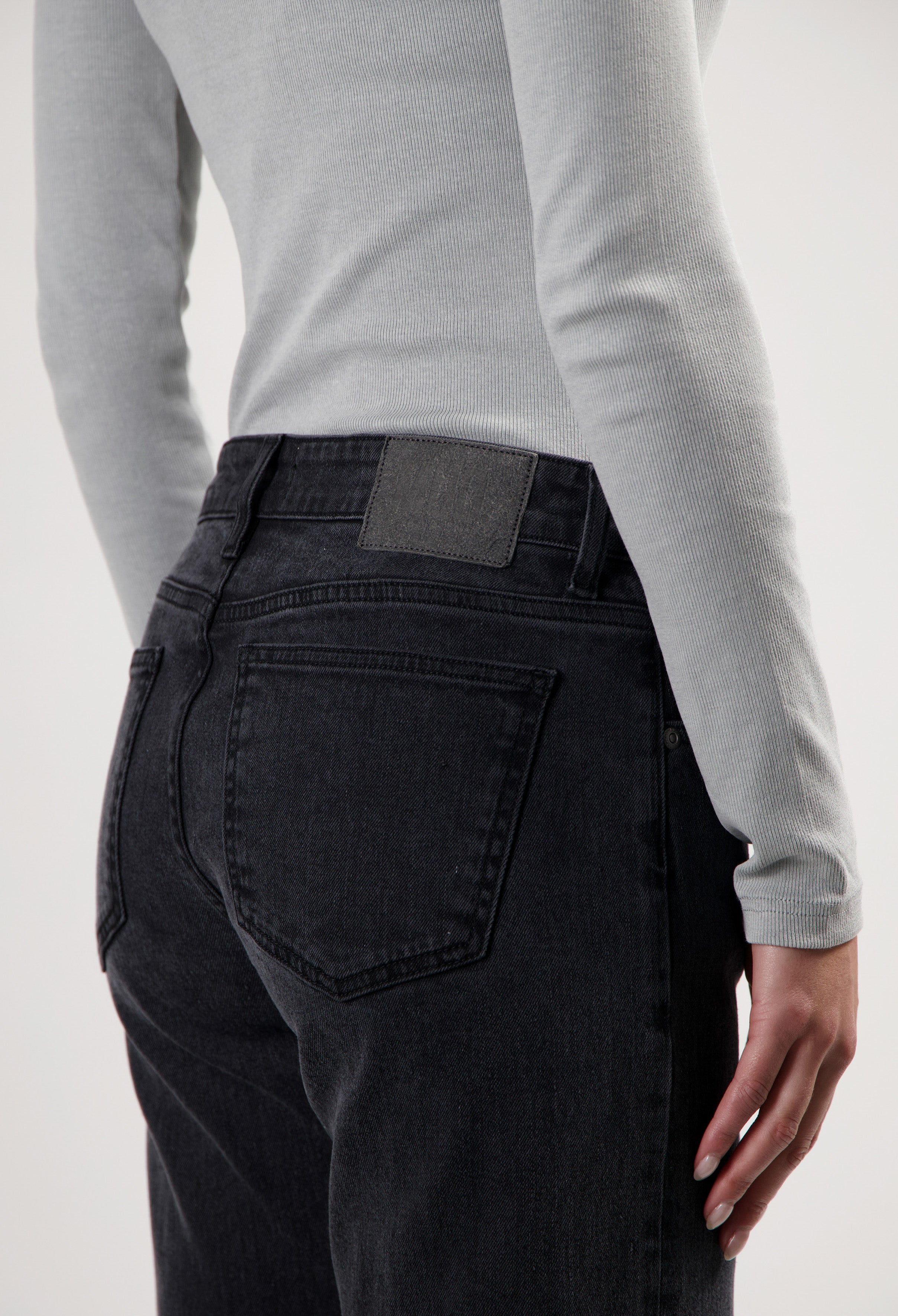 Dark blue jeans with a high-waisted fit, worn with a light gray ribbed long-sleeve top.