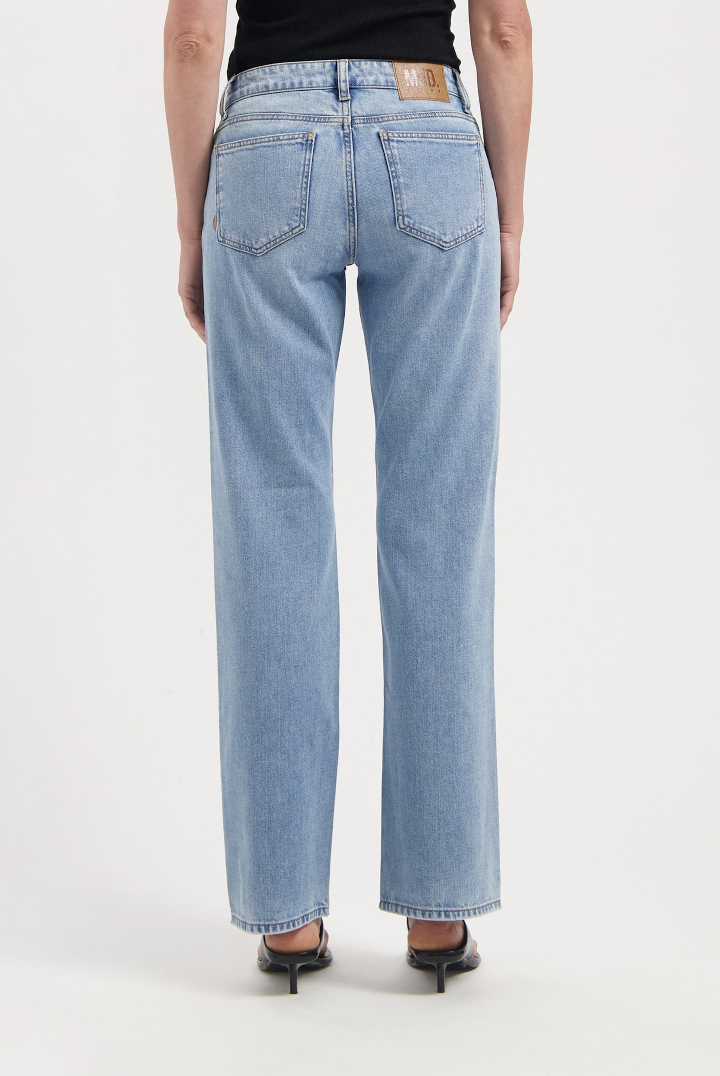 Light blue, straight-leg jeans made from organic cotton, featuring a high waist, shown worn with a black top and heels.