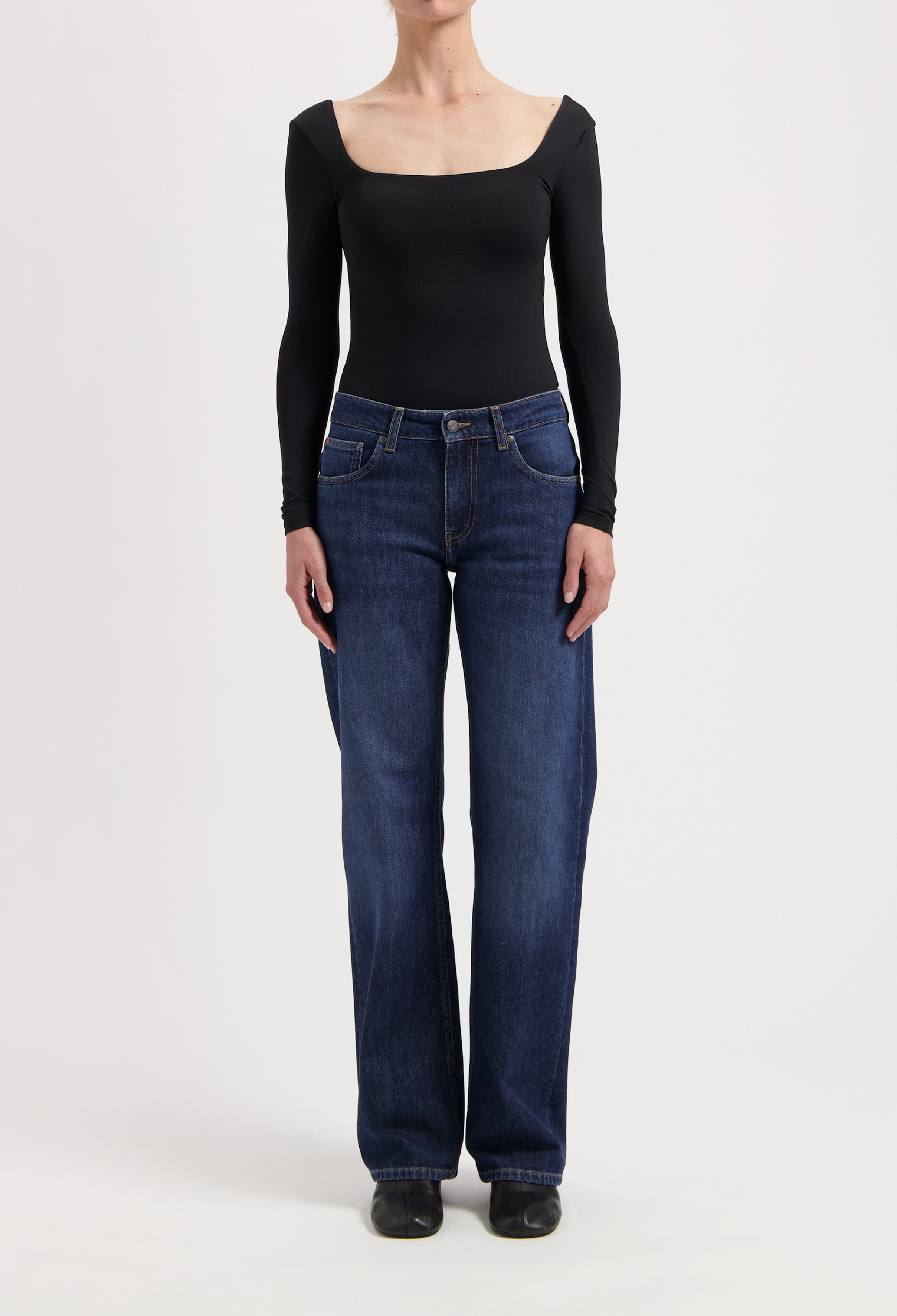 Dark blue, wide-leg denim jeans paired with a sleek black, long-sleeve top, showcasing a modern casual outfit style.