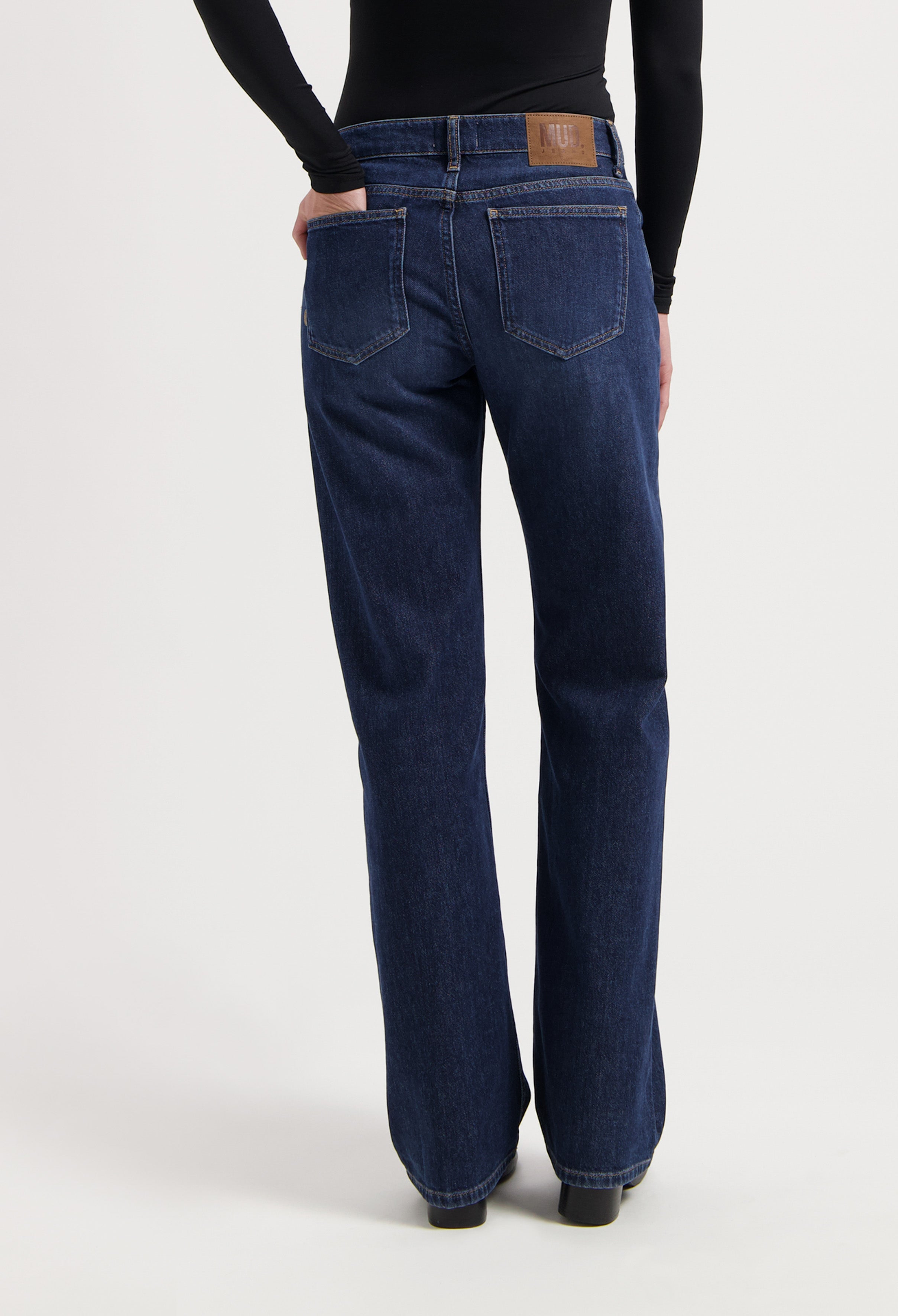 Dark blue straight-leg jeans made from organic cotton, showcasing a back view with intricate stitching and leather patch.