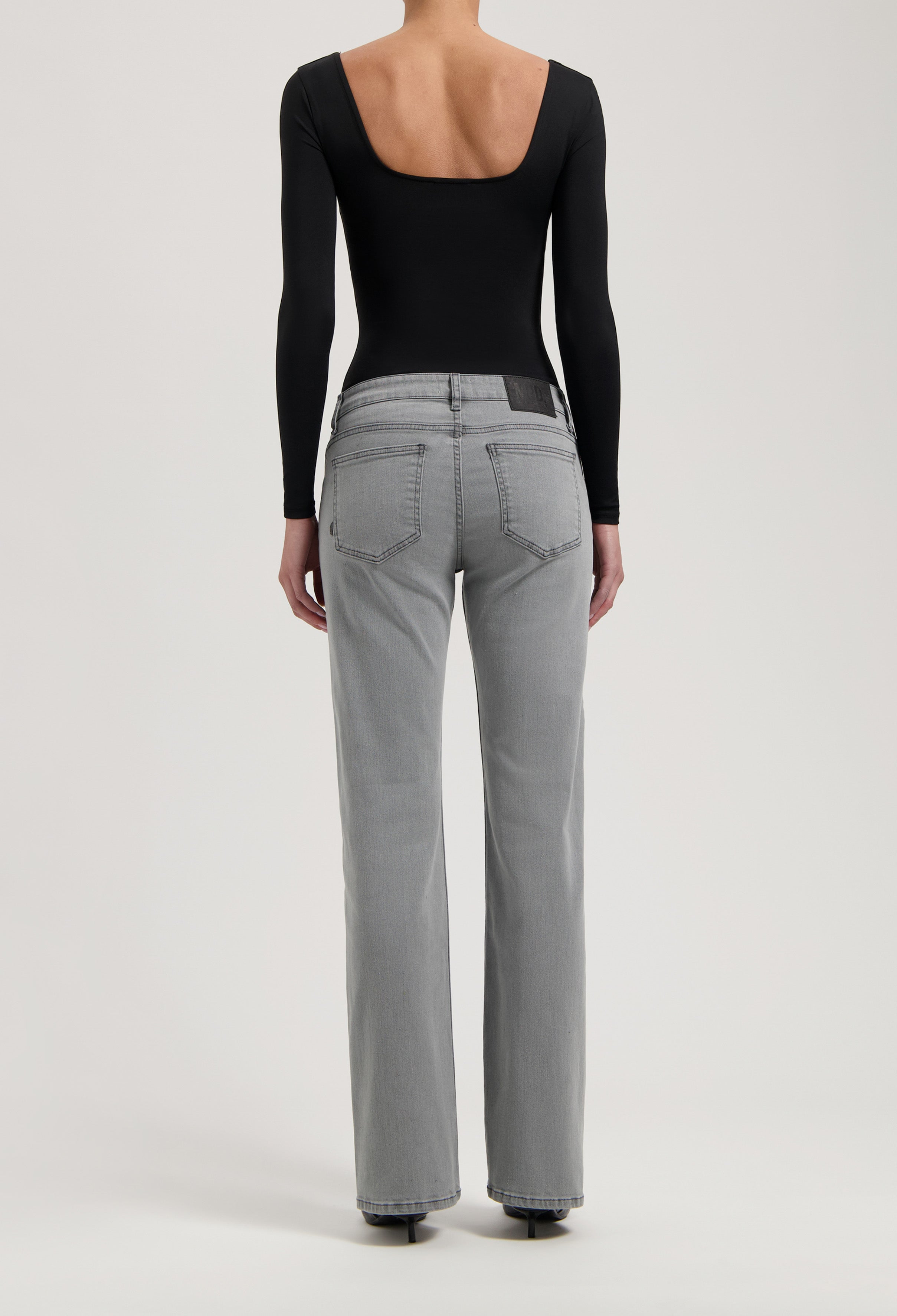 Back view of gray straight-leg jeans paired with a sleek black long-sleeve bodysuit, highlighting casual elegance.