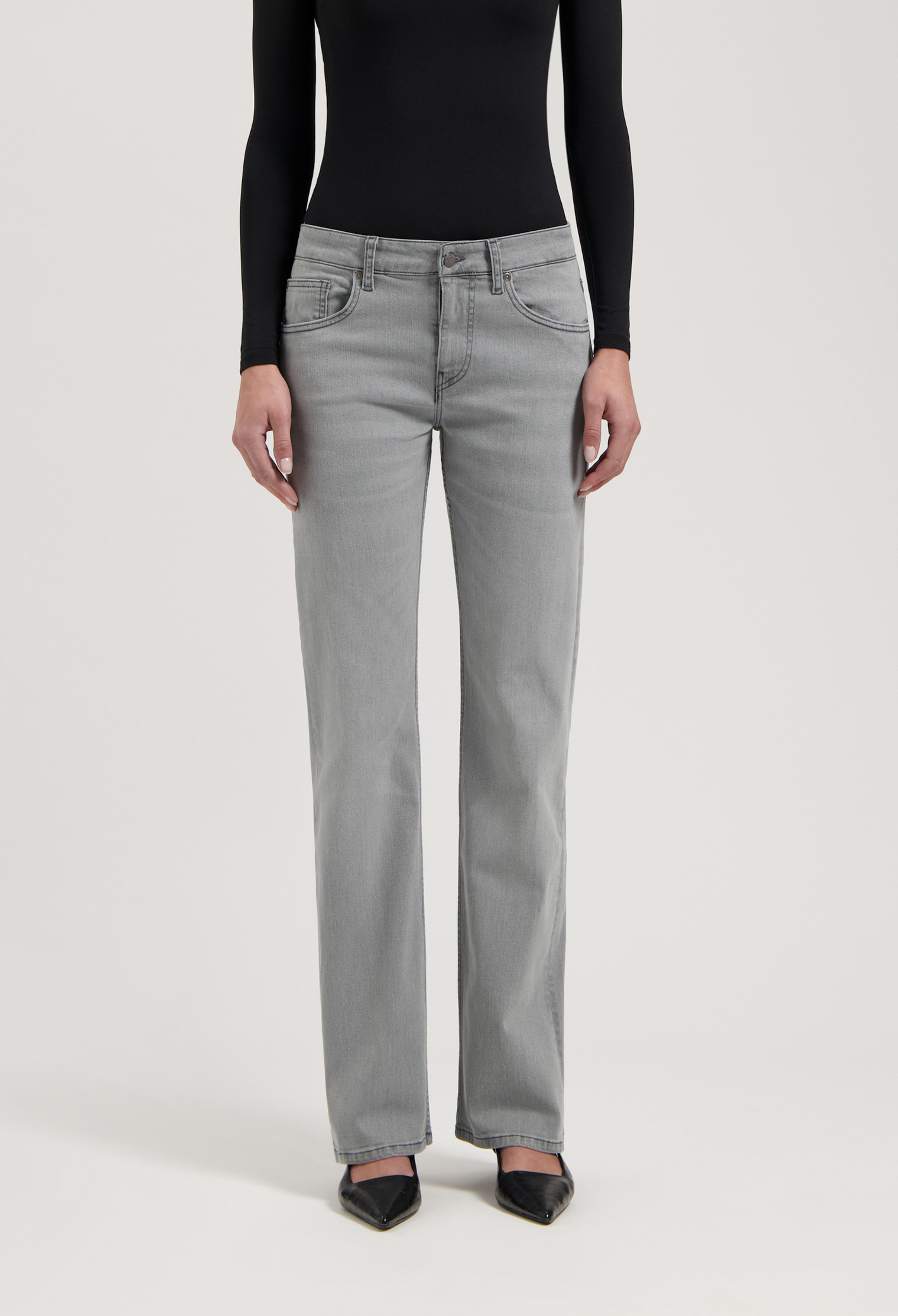 Gray straight-leg jeans paired with a sleek black long-sleeve top and pointed black heels for a modern look.