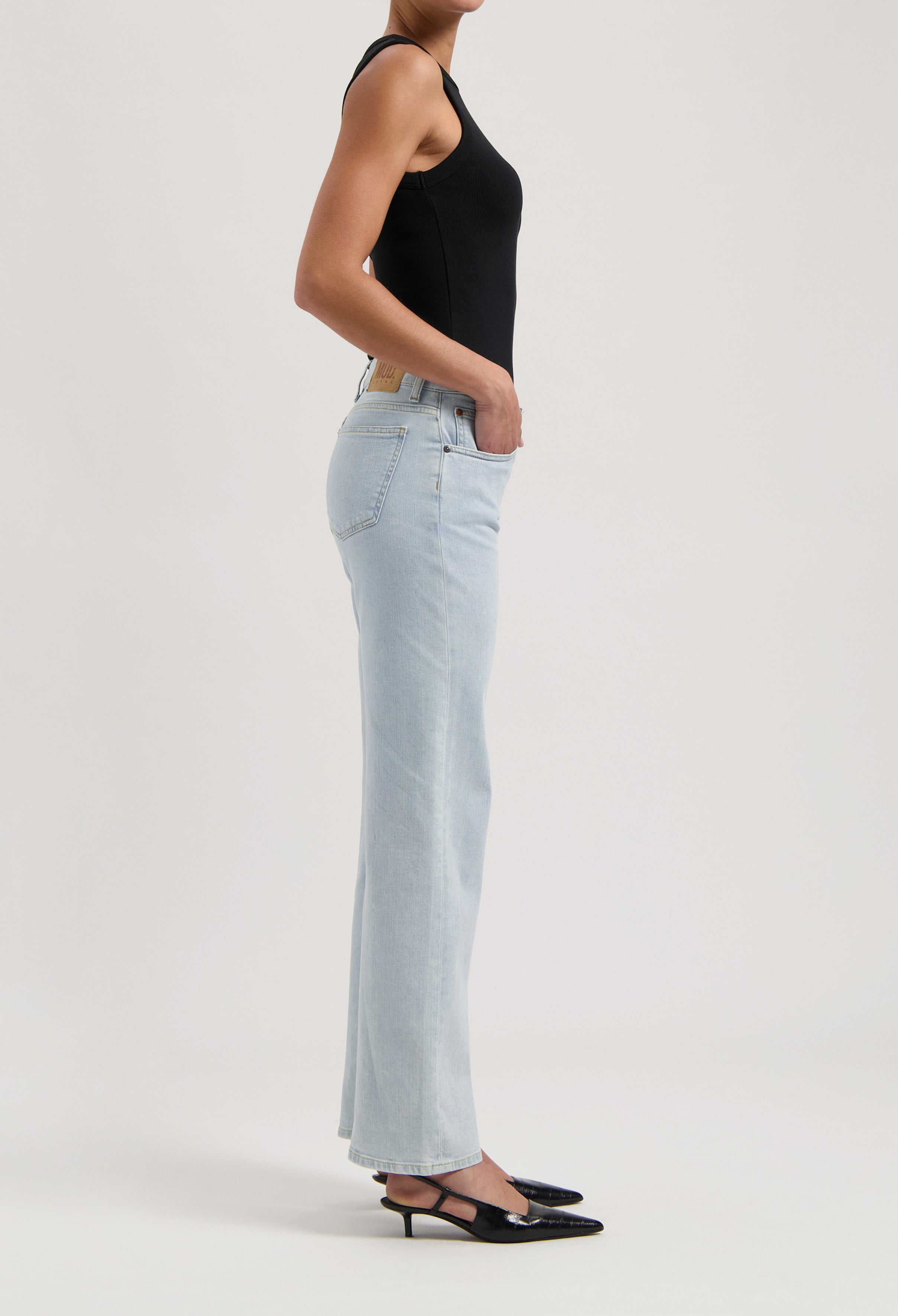 Model wearing light blue high-waisted jeans with a fitted black sleeveless top, showcasing a trendy and casual style.