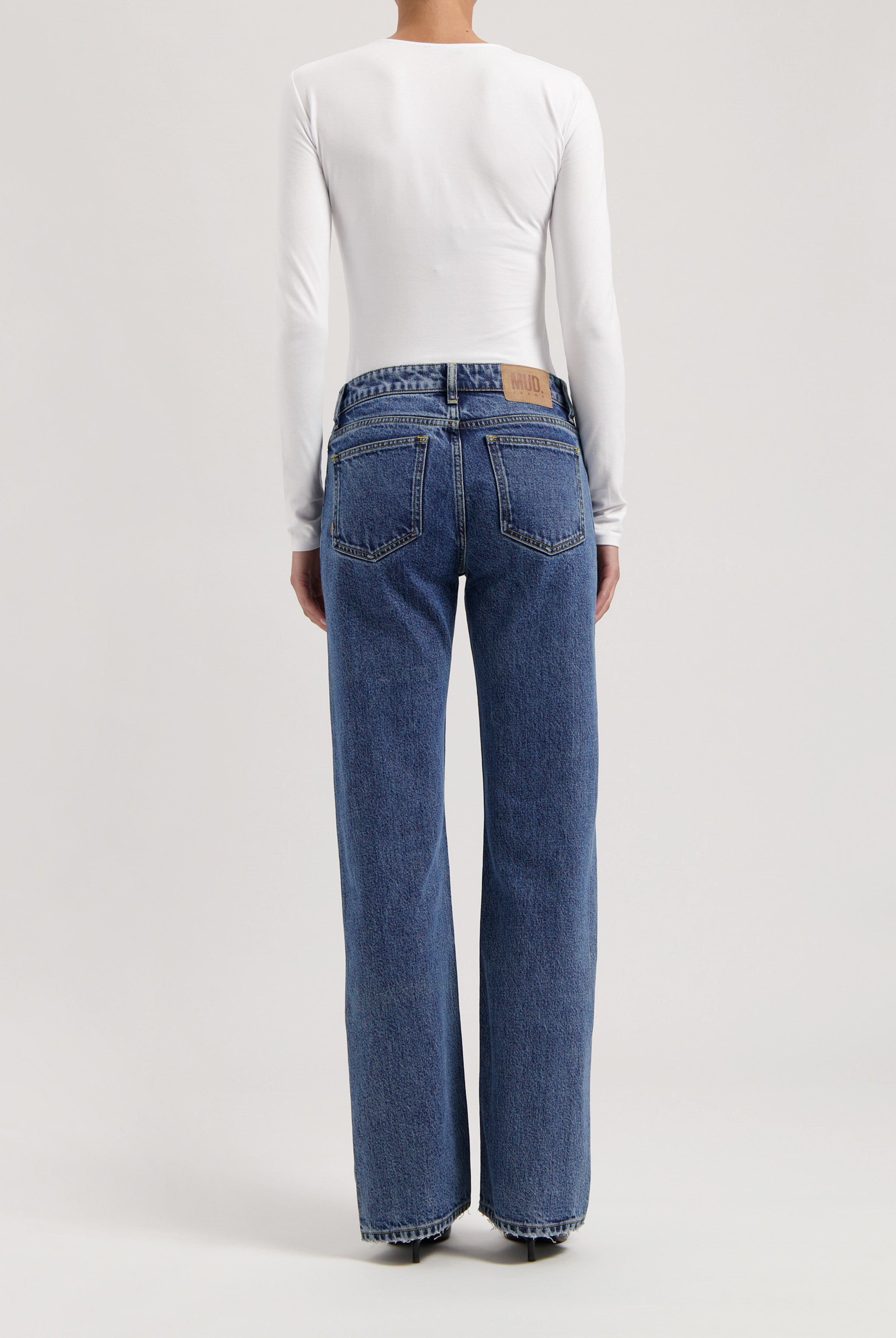 Long-sleeve white top paired with MUD Jeans, showcasing high-waisted, wide-leg organic denim in classic blue.