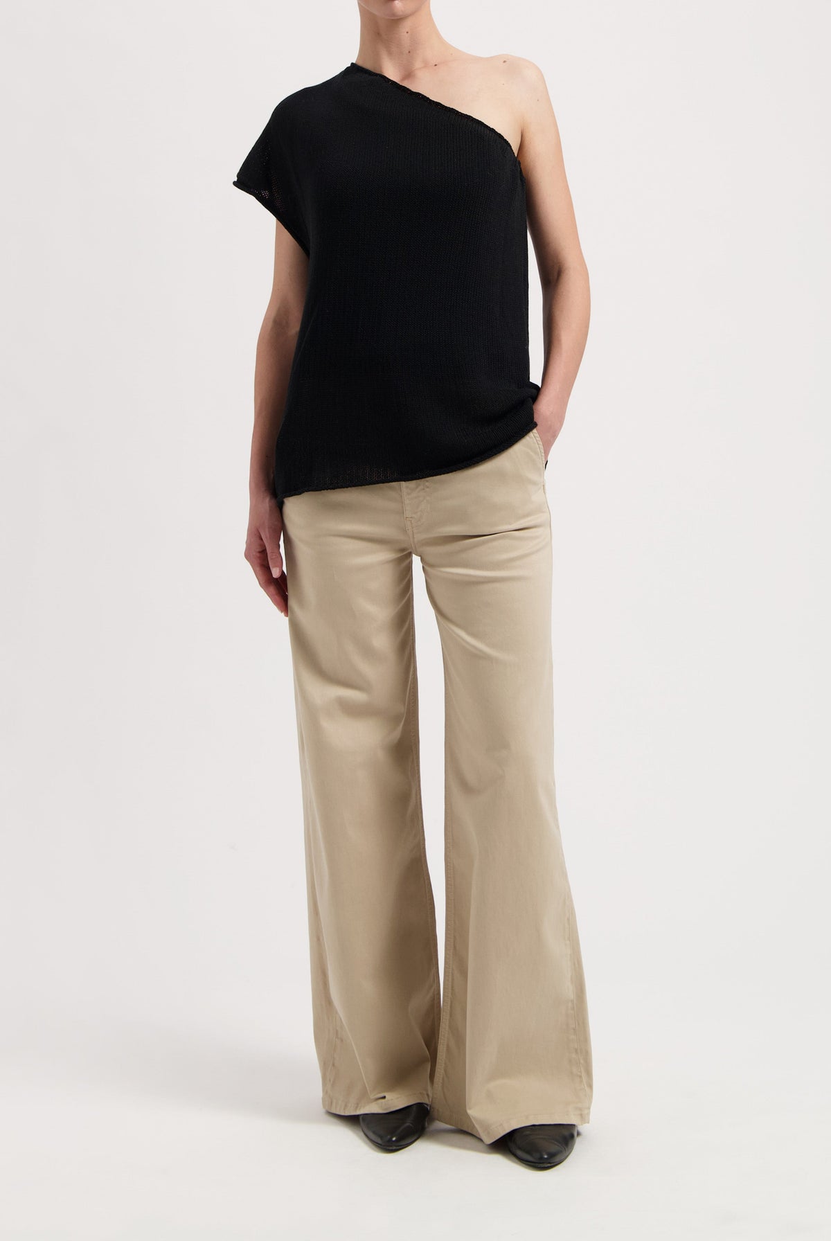 One-shoulder black top paired with wide-leg beige trousers, showcasing casual yet elegant modern fashion style.