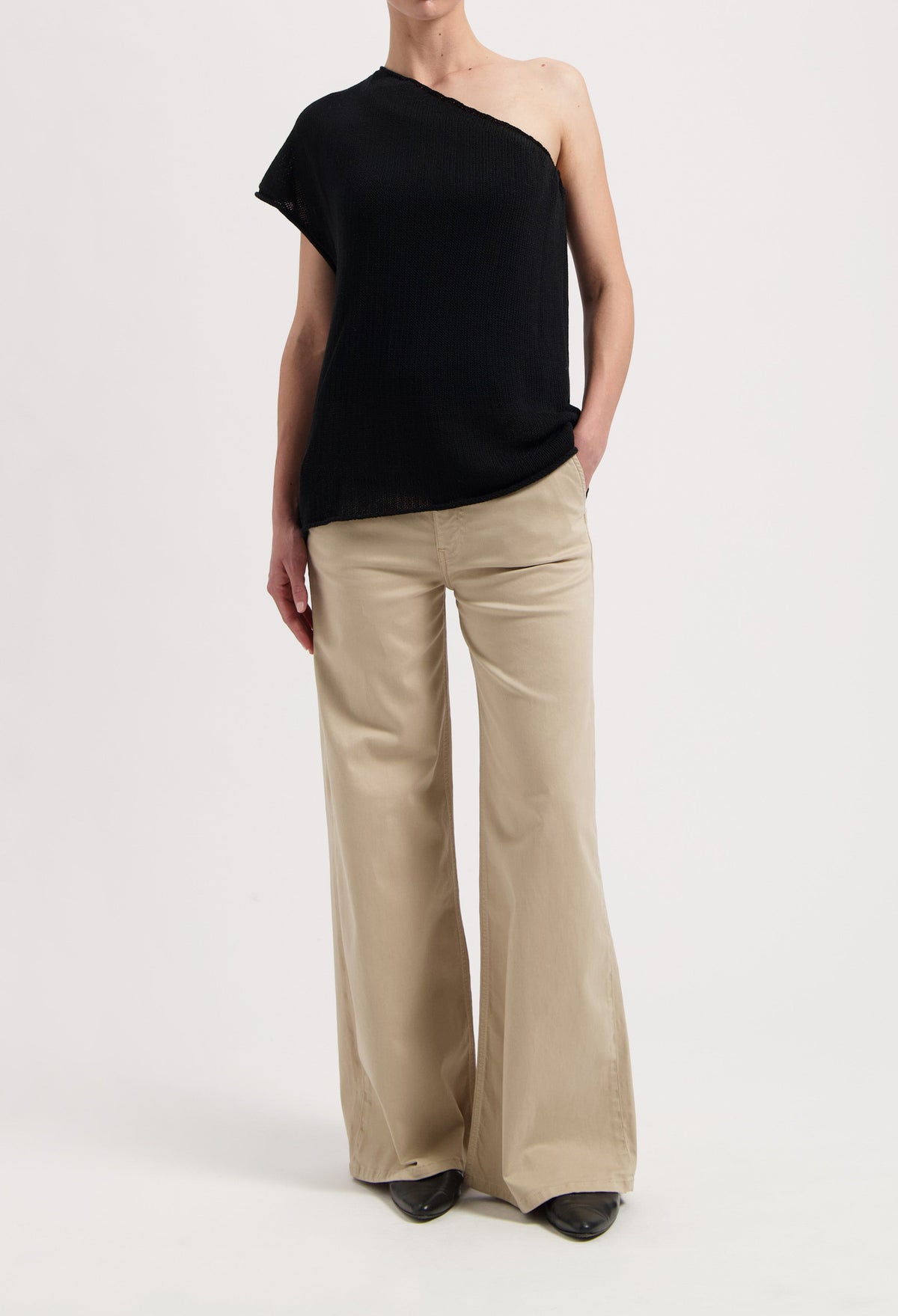 One-shoulder black top paired with wide-leg beige trousers, showcasing casual yet elegant modern fashion style.