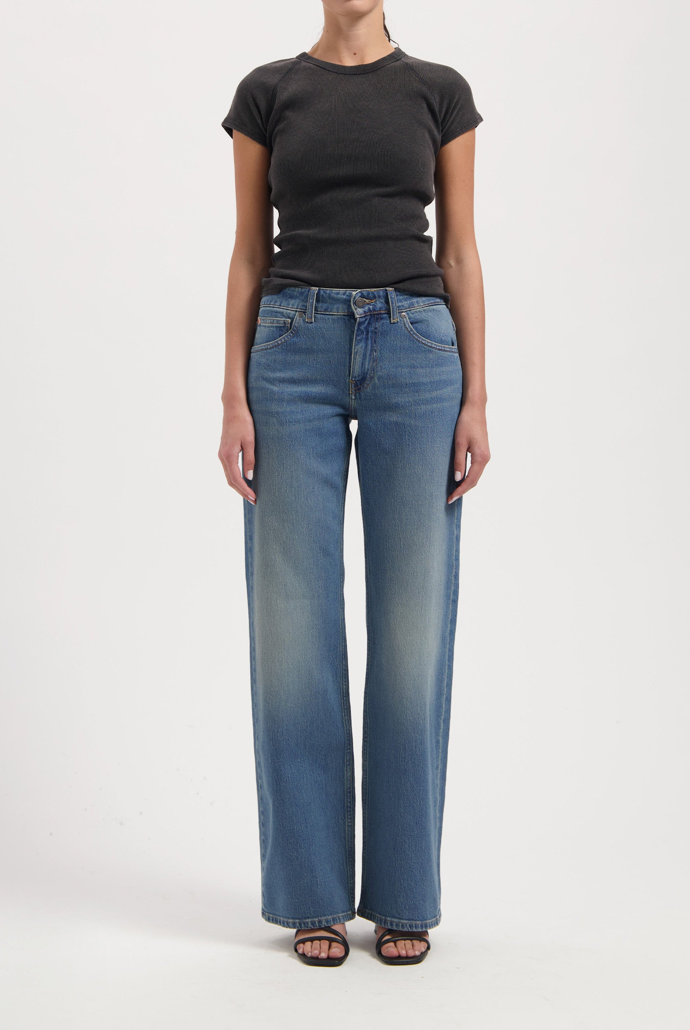 Wide-leg blue jeans with faded effect, paired with a fitted black short-sleeve top, worn by a model against a plain background.